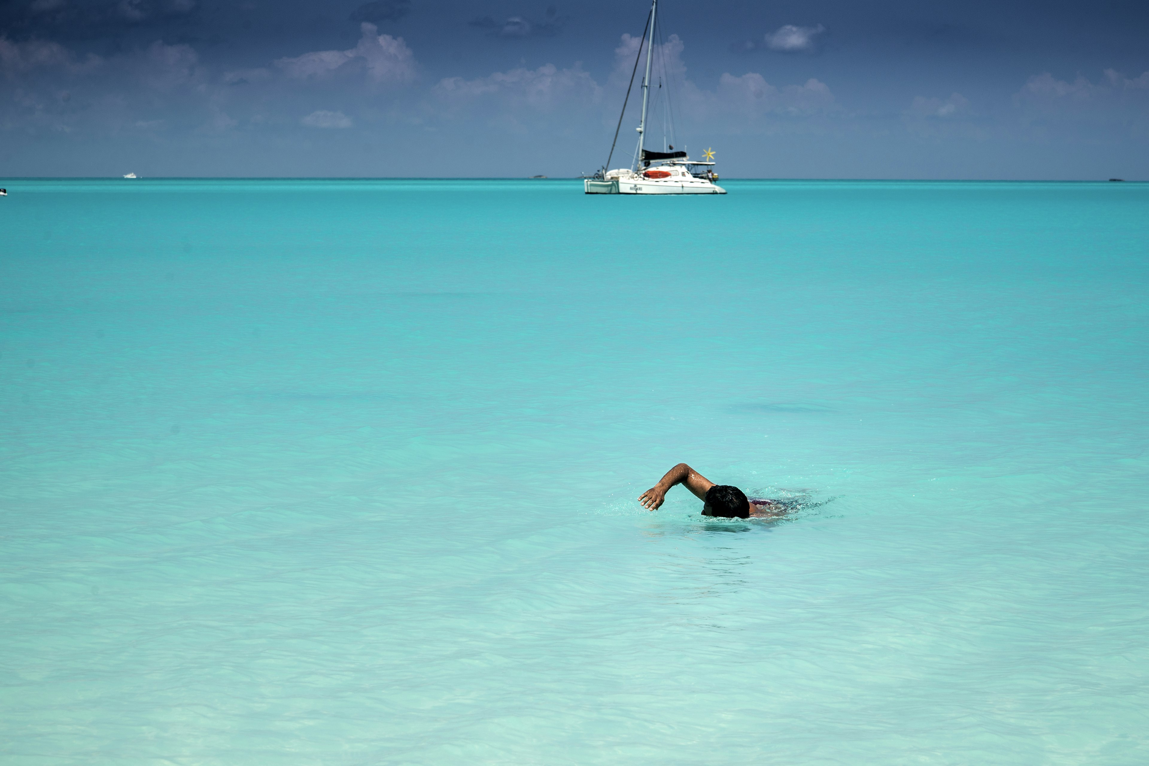 Man swimming to shore in perfectly clear turquoise-colored water.