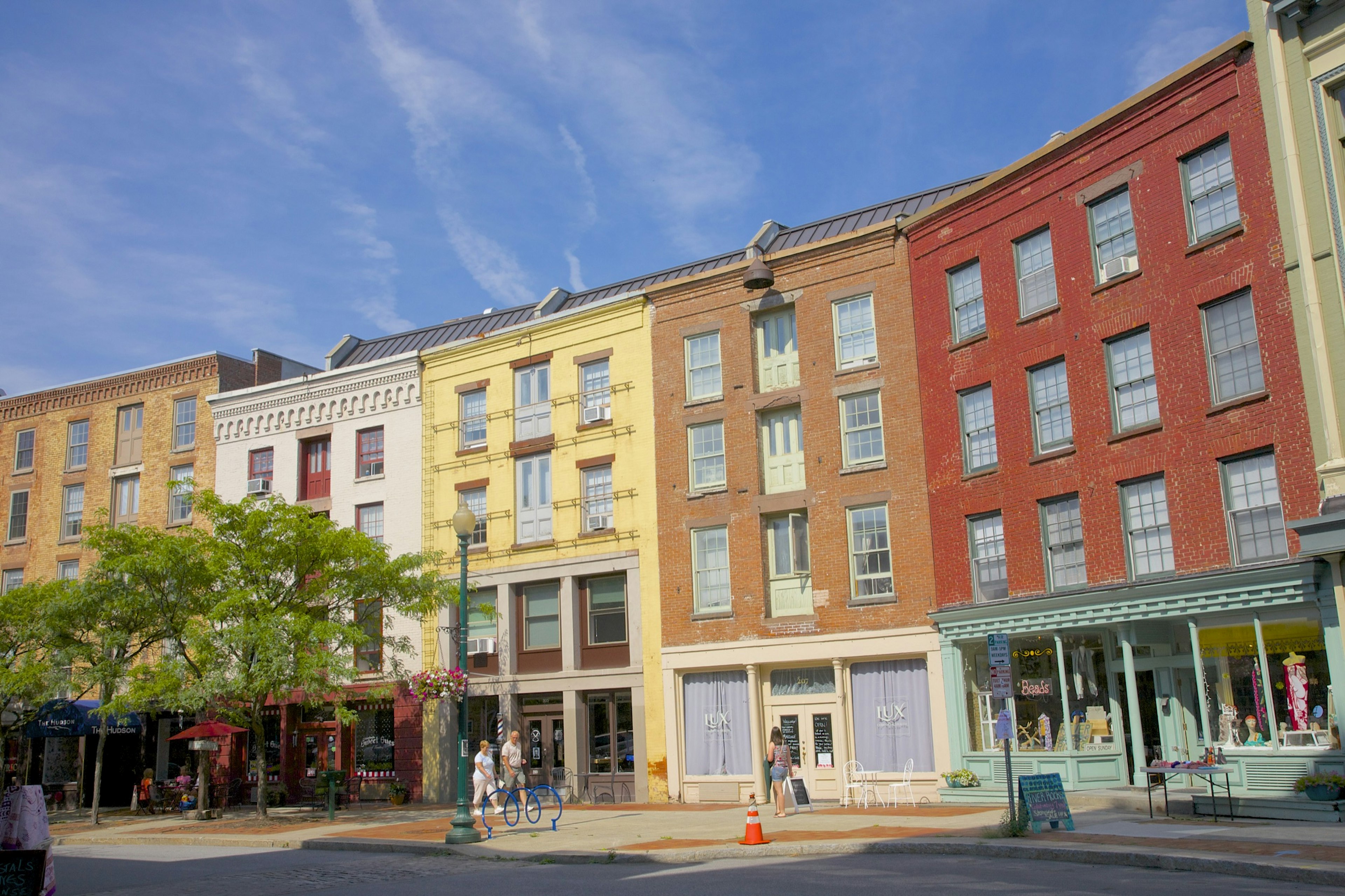 A few people walk in front of the colorful facades on curved street of Antiques Row on River Street in downtown Troy.