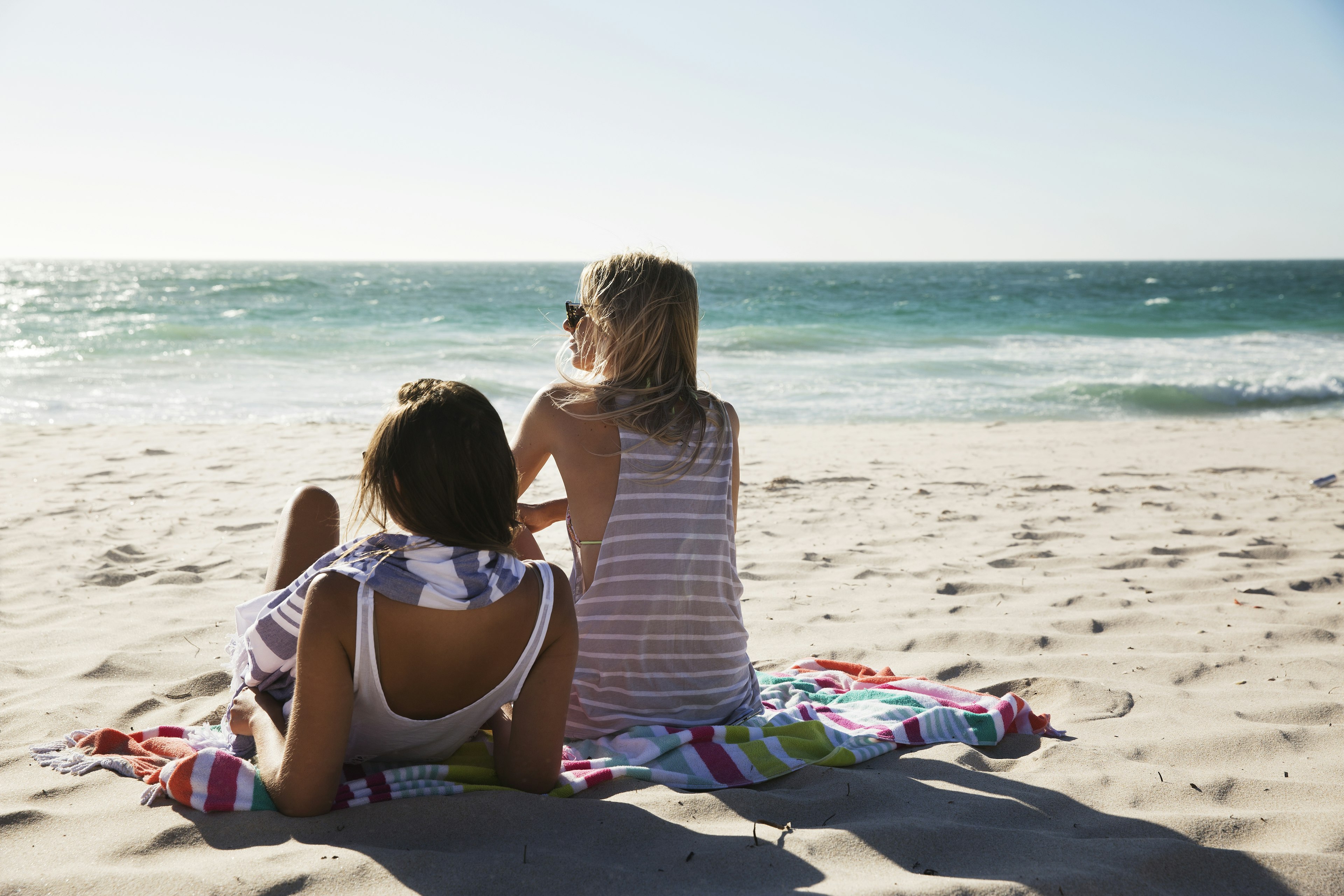 Group of friends and couple walking and hanging out on the beach, waring shorts and tops