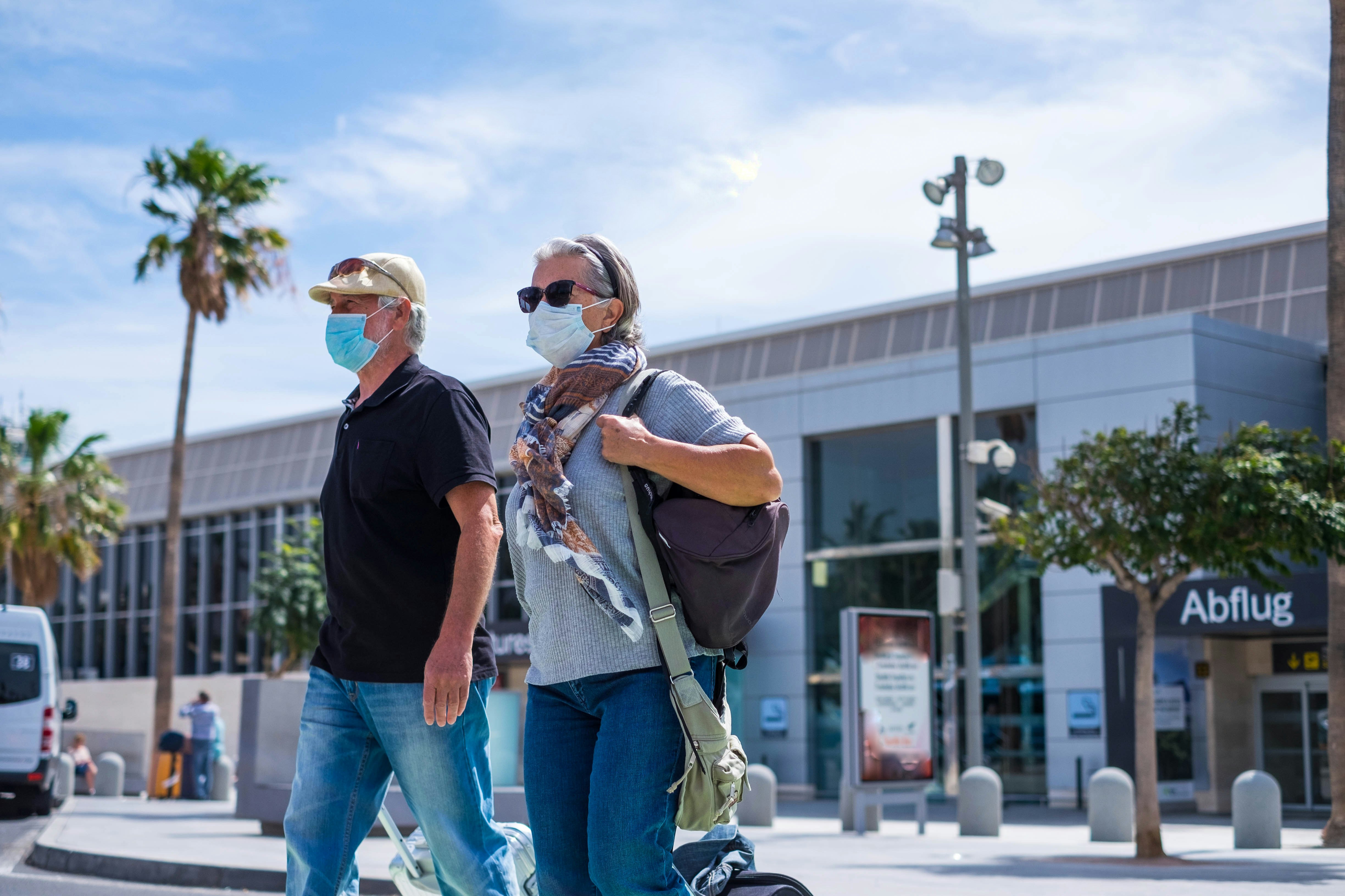 two seniors walking with their baggage and wearing medical mask to prevent covid-19