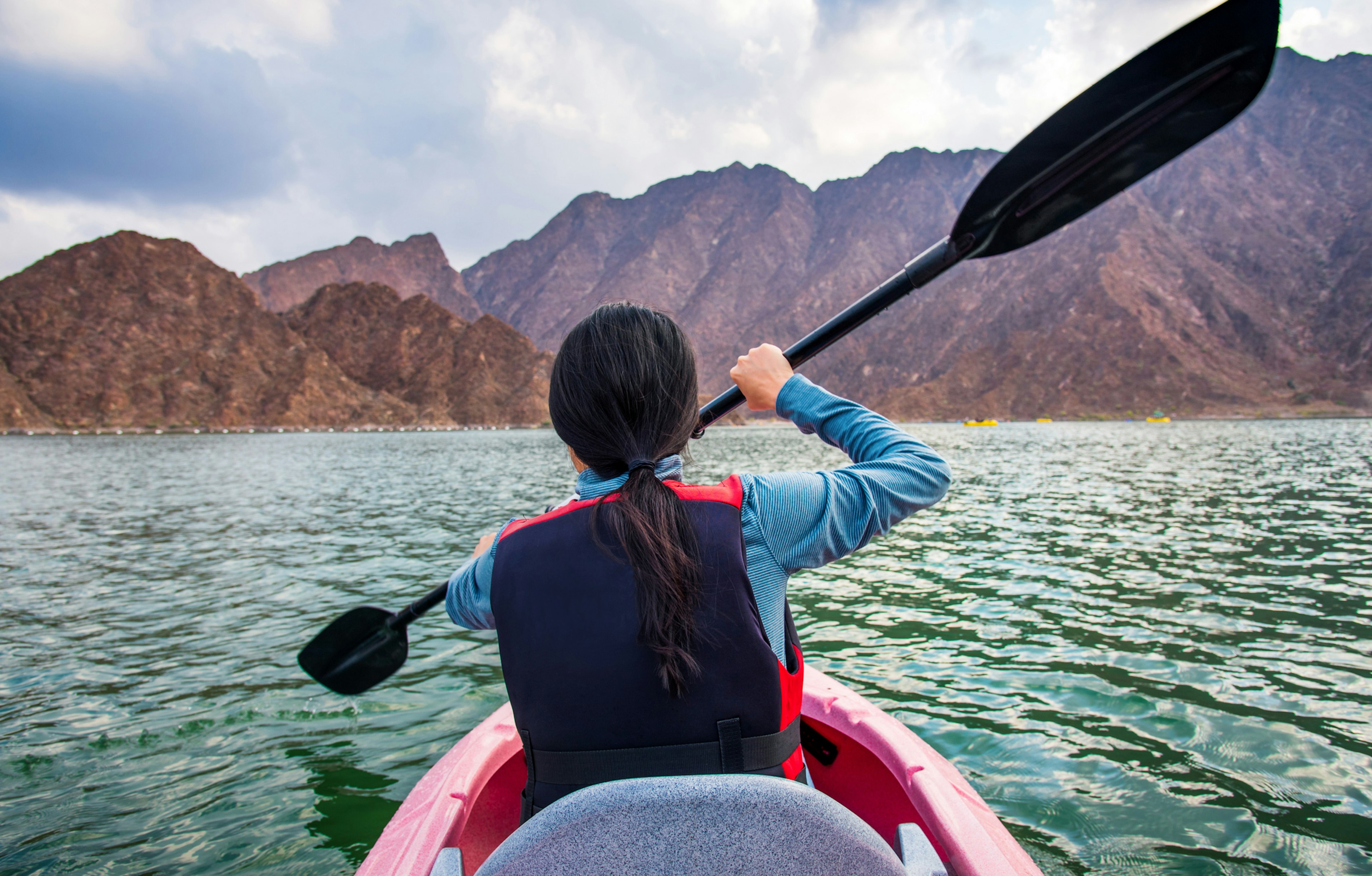 A rear shot of a woman kayaking in a lake