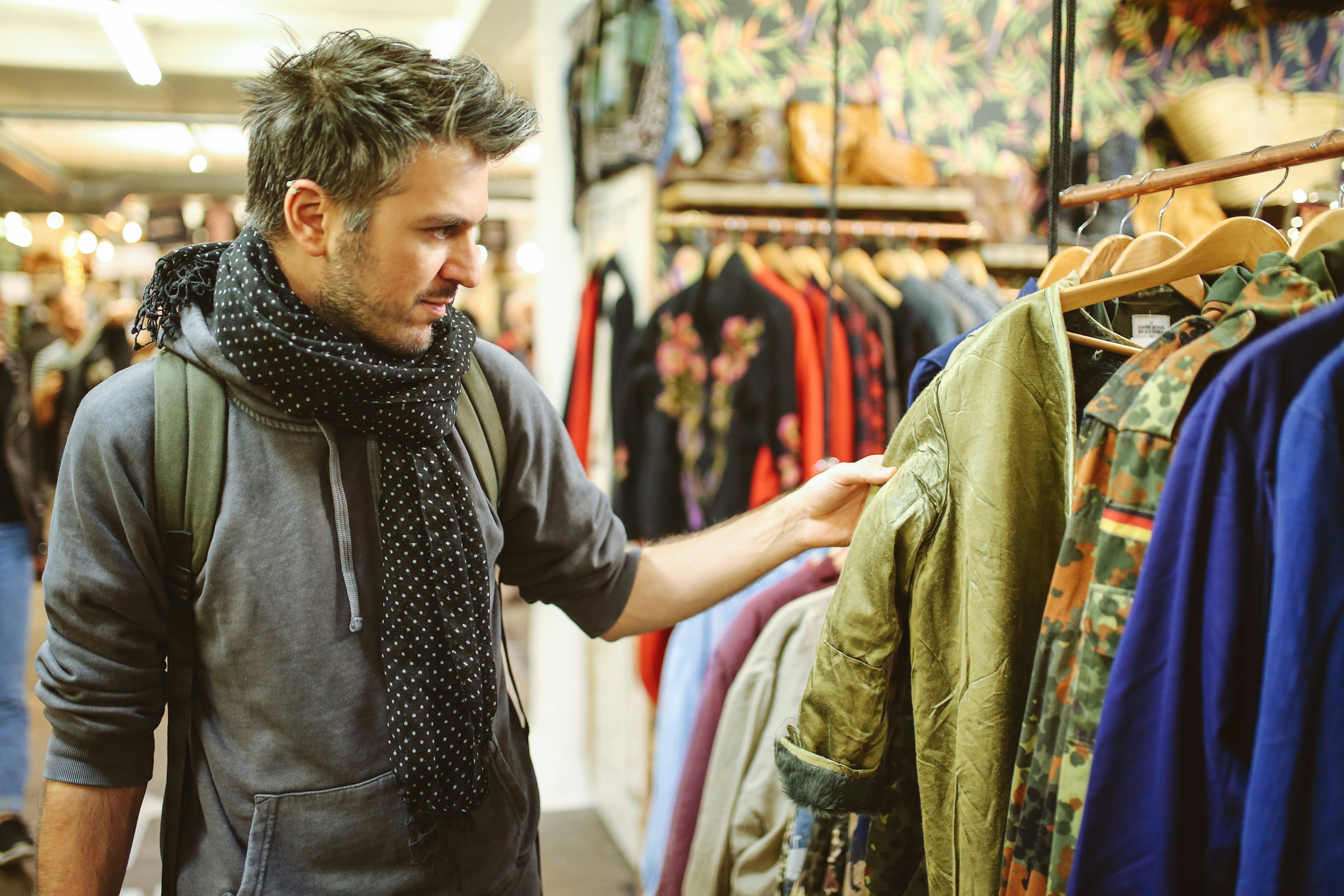 A white man browses through a clothes rail in a second-hand market