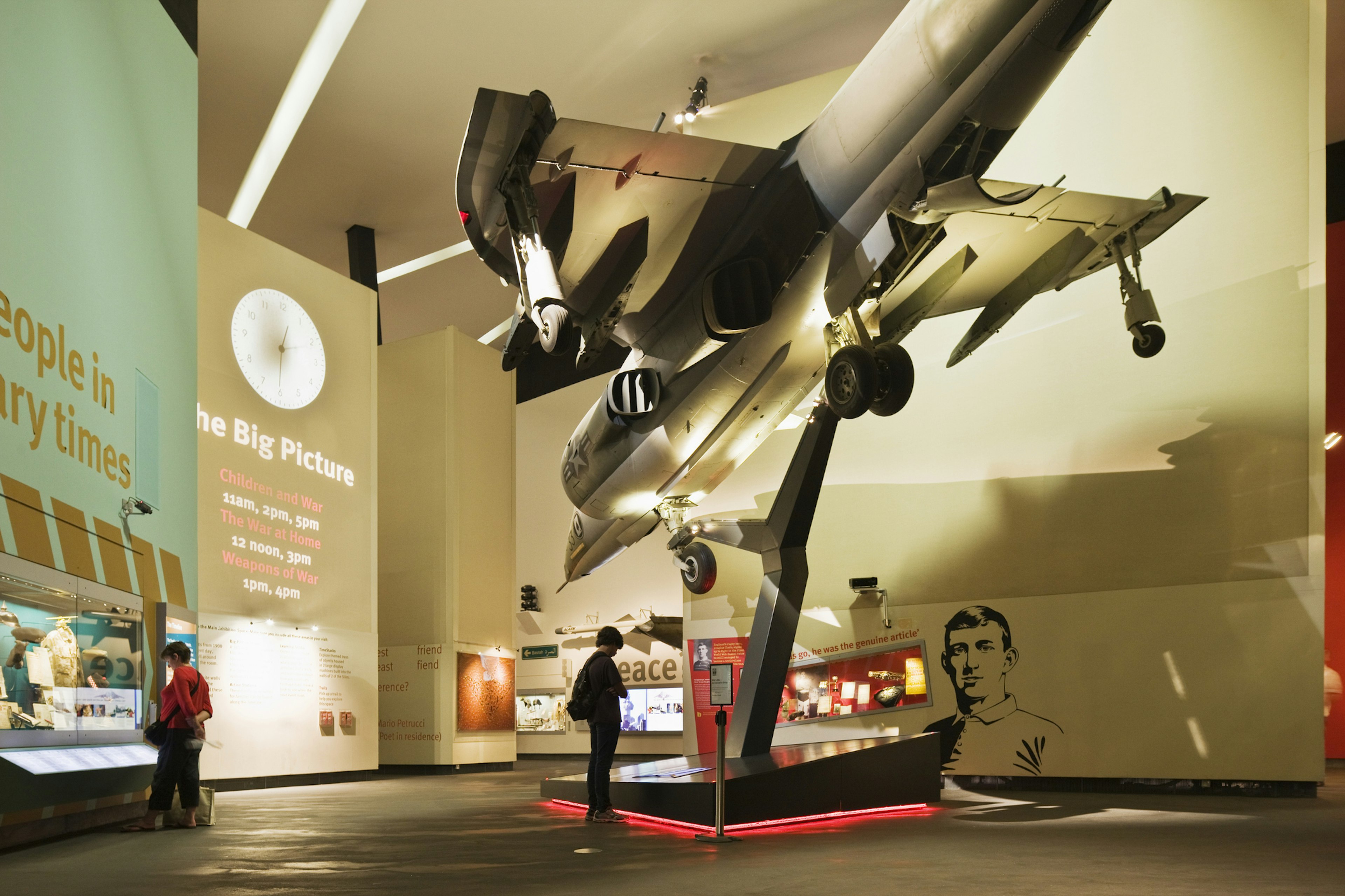 A museum display with a jet suspended above the ground pointing downwards. Two people are admiring the exhibits