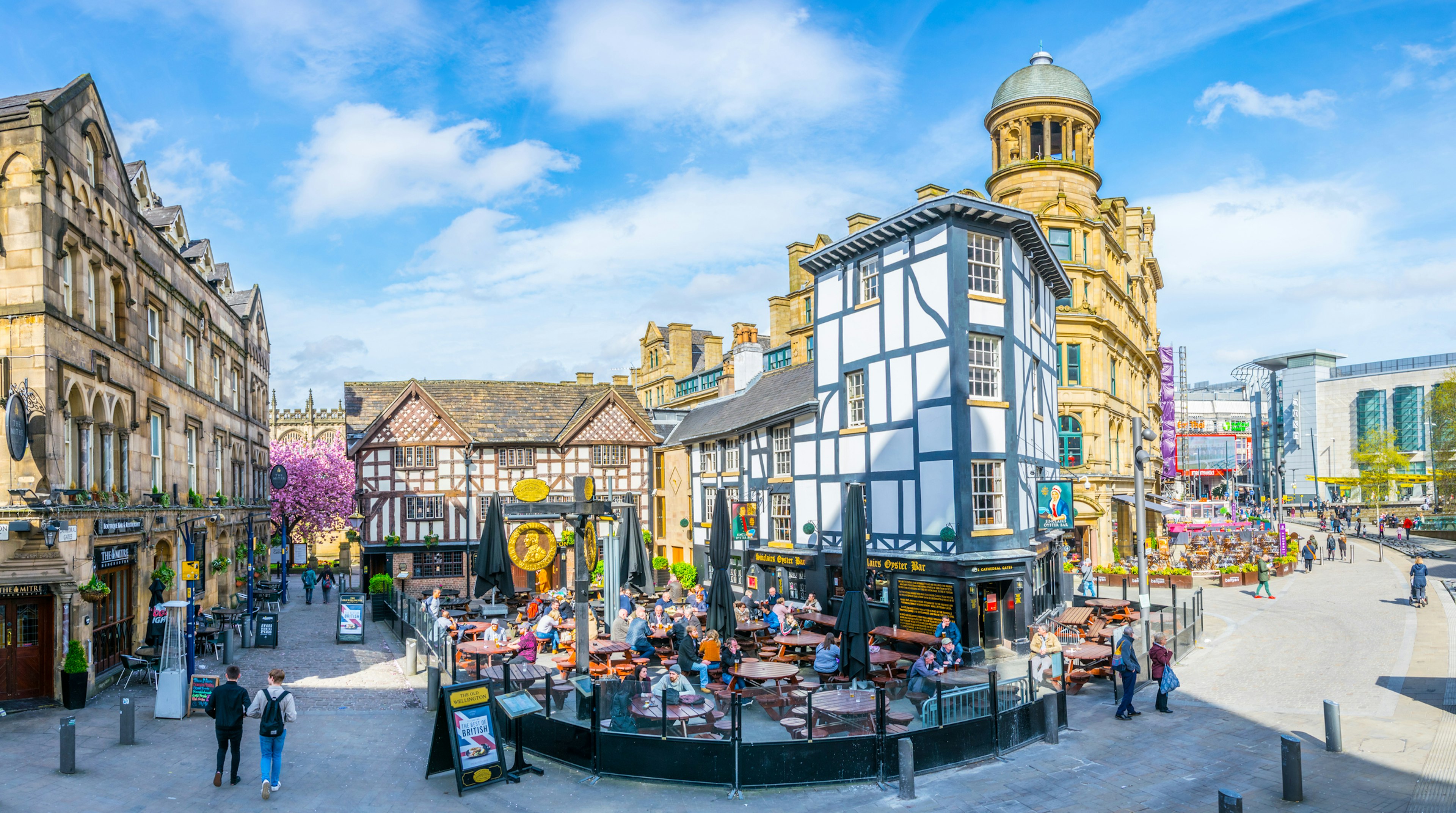 Restaurants with outside tables full of people on the Shambles square in Manchester, England