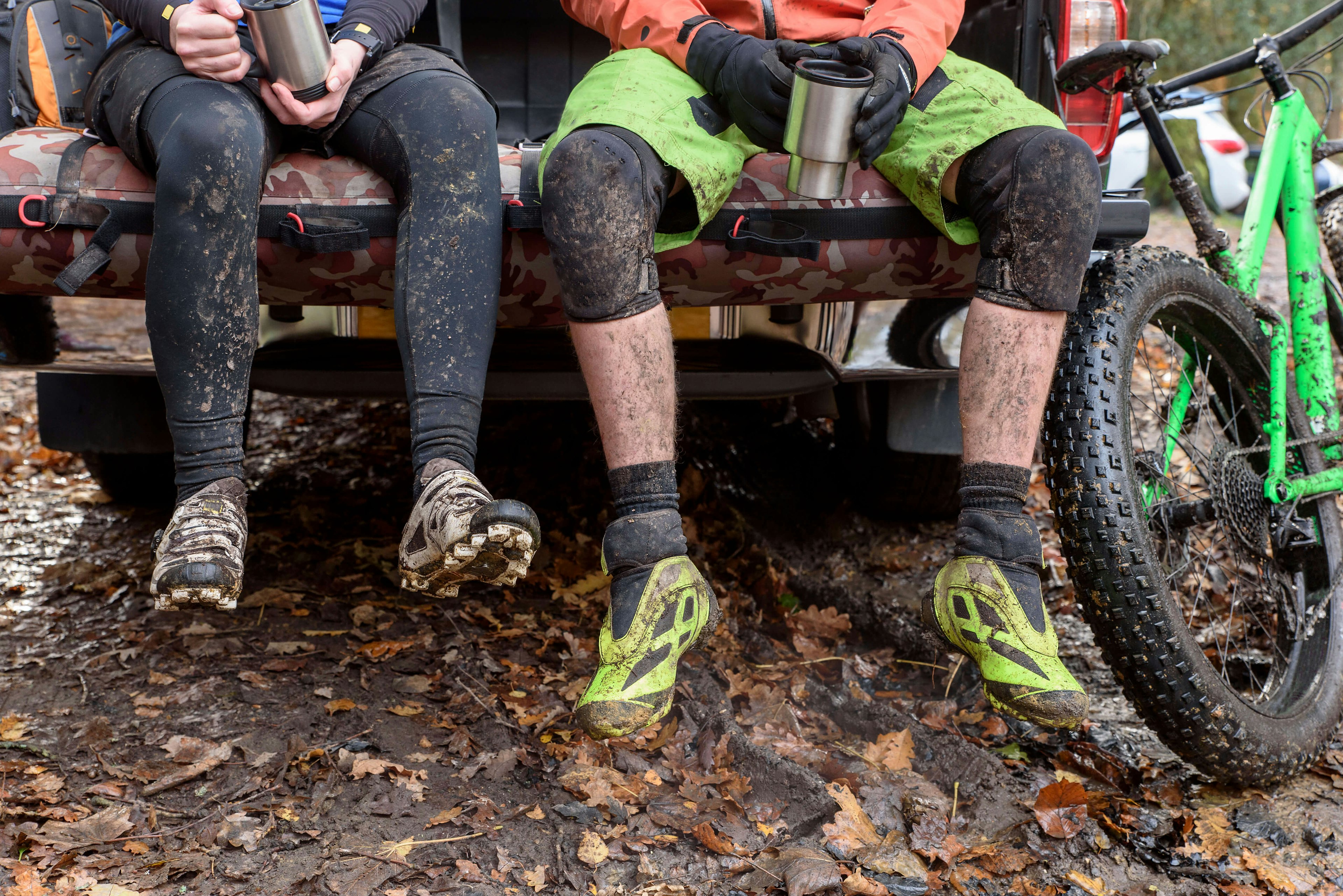 Muddy legs of Caucasian couple sitting in a pickup truck near a bicycle