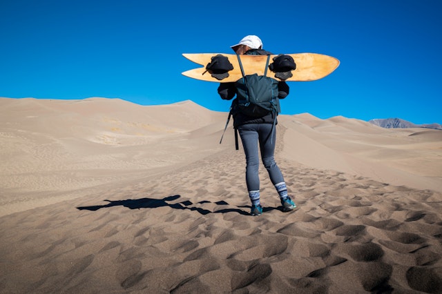 A female holds a sand board at Great Sand Dunes National Park, Colorado, USA