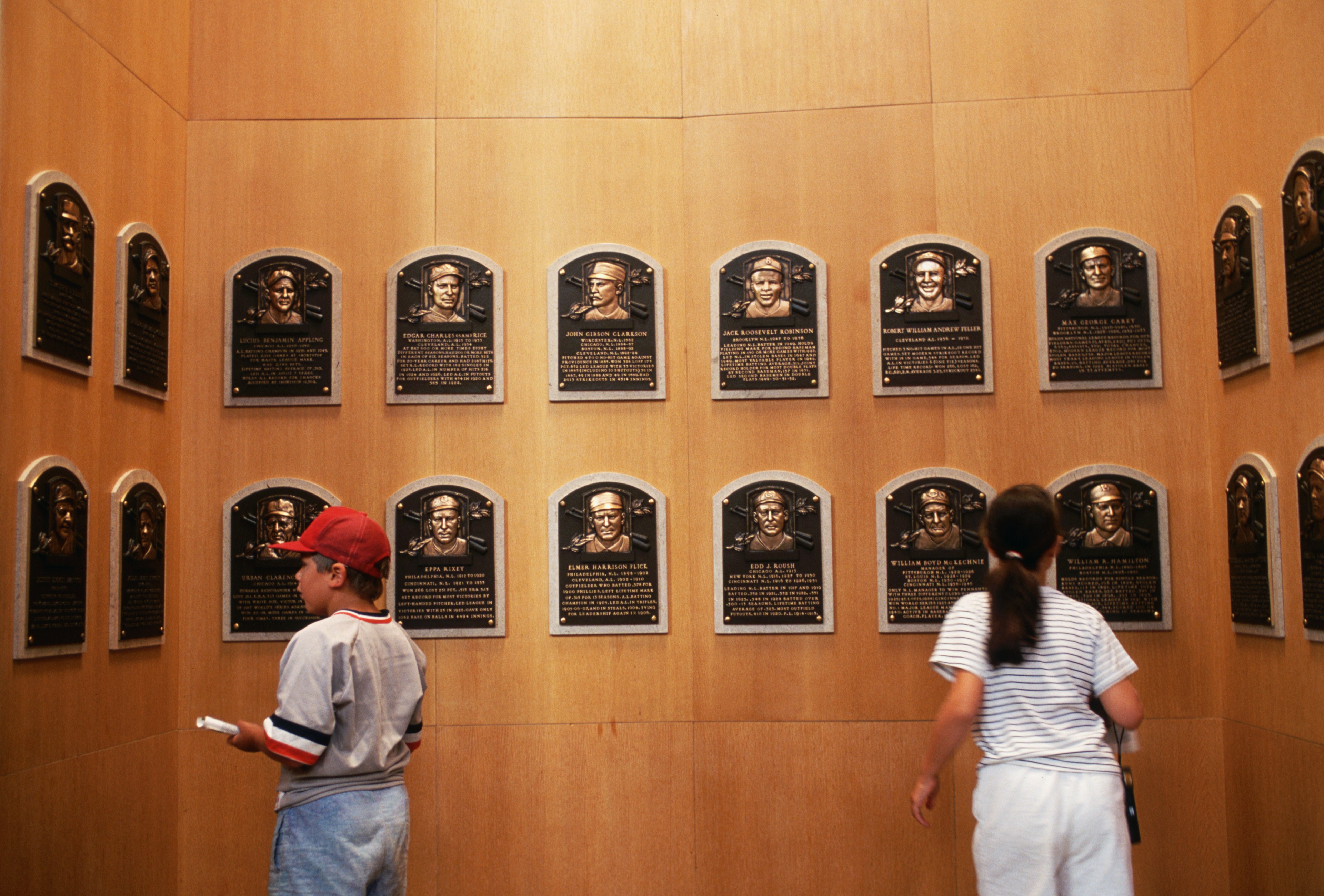 A young boy and girl look at name plaques of baseball players who have been inducted into the Baseball Hall of Fame