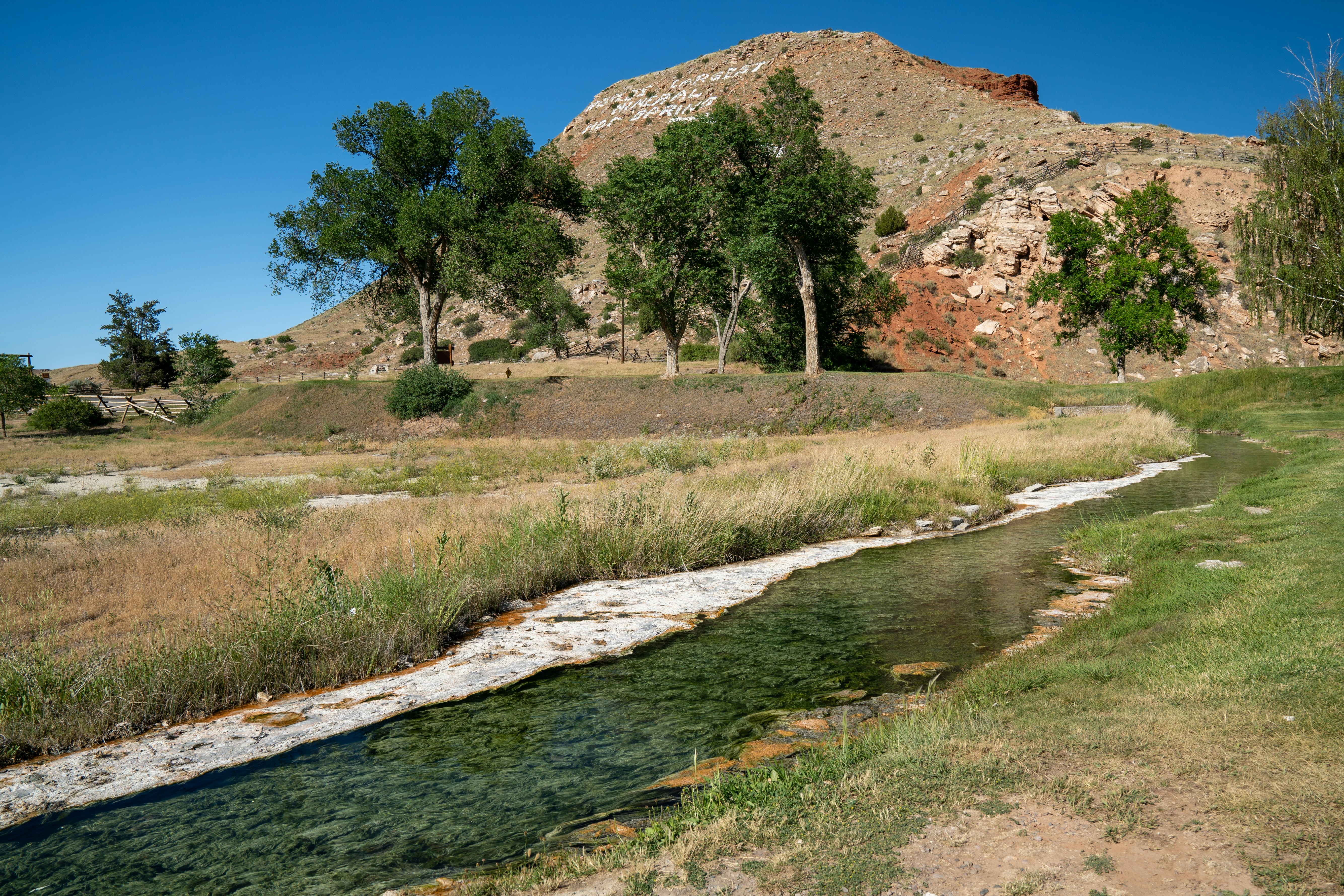 A small creek winds through a meadow, with a small mountain in the background – Hot Springs State Park in Thermopolis, Wyoming, a geothermal area in Hot Springs County