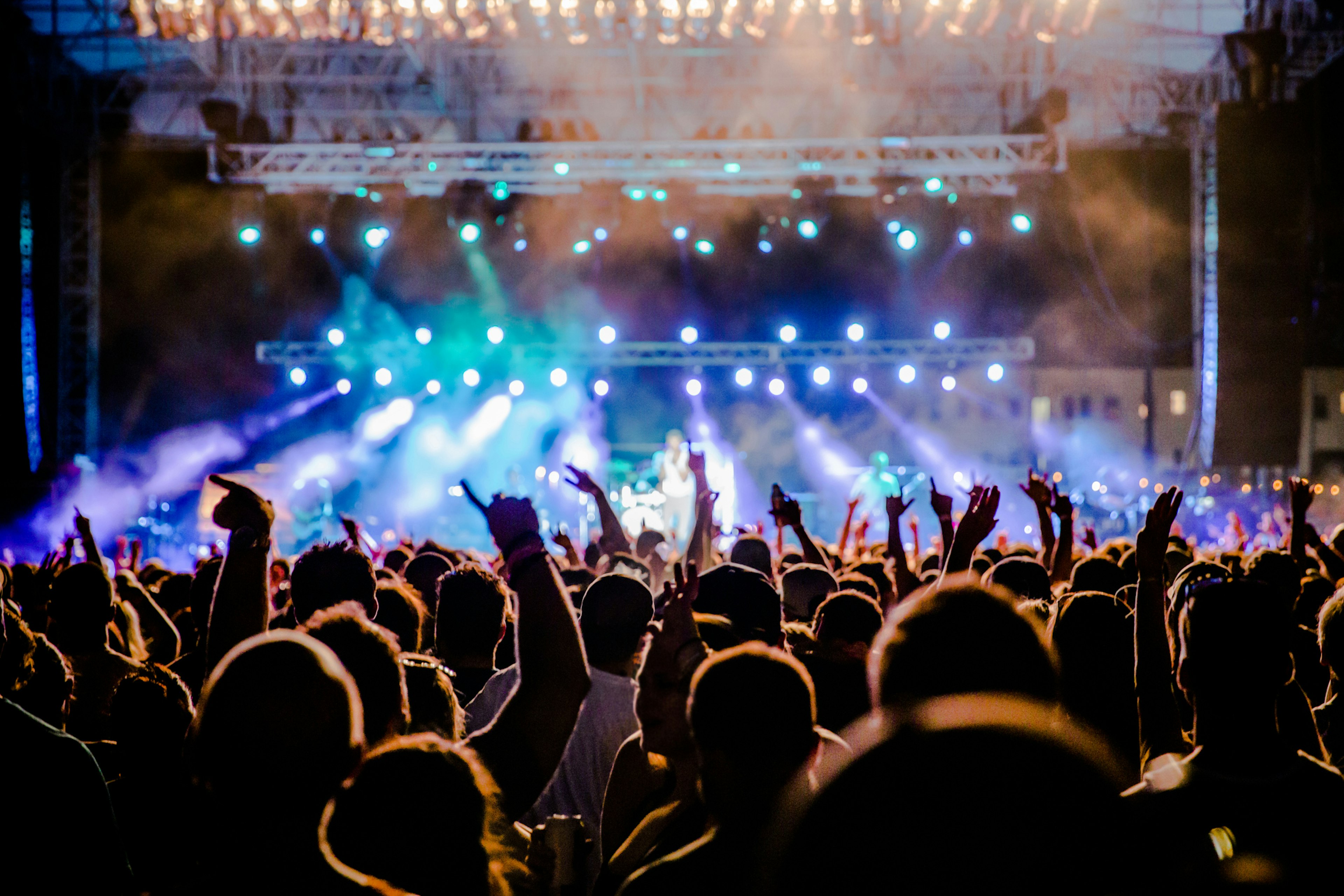 A view towards the stage over the heads of festival goers at night