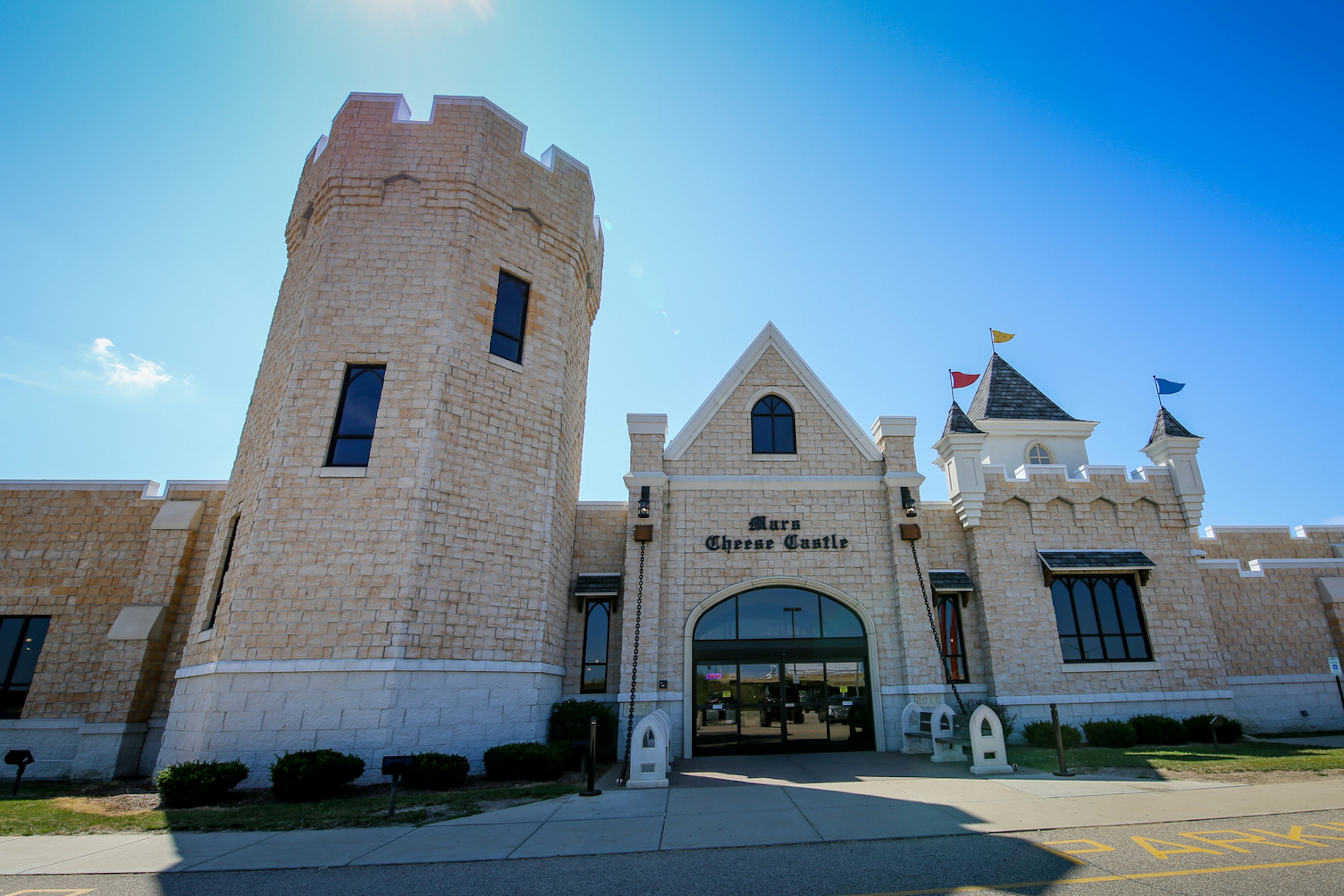 A pale castle with pennants flying from its turrets on a clear day