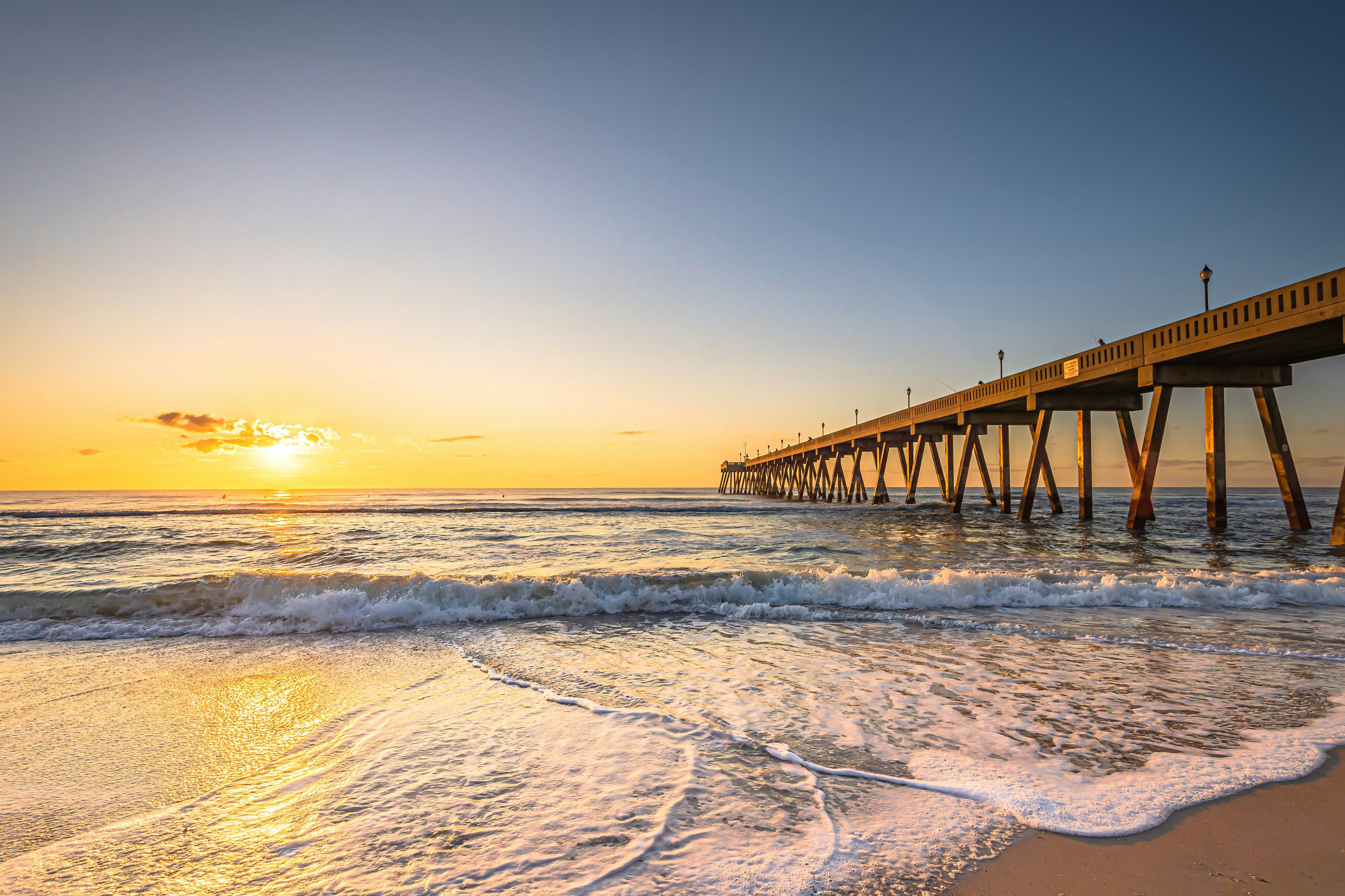 Wrightsville Beach at sunset with the pier stretching out in the sea on the right hand side.