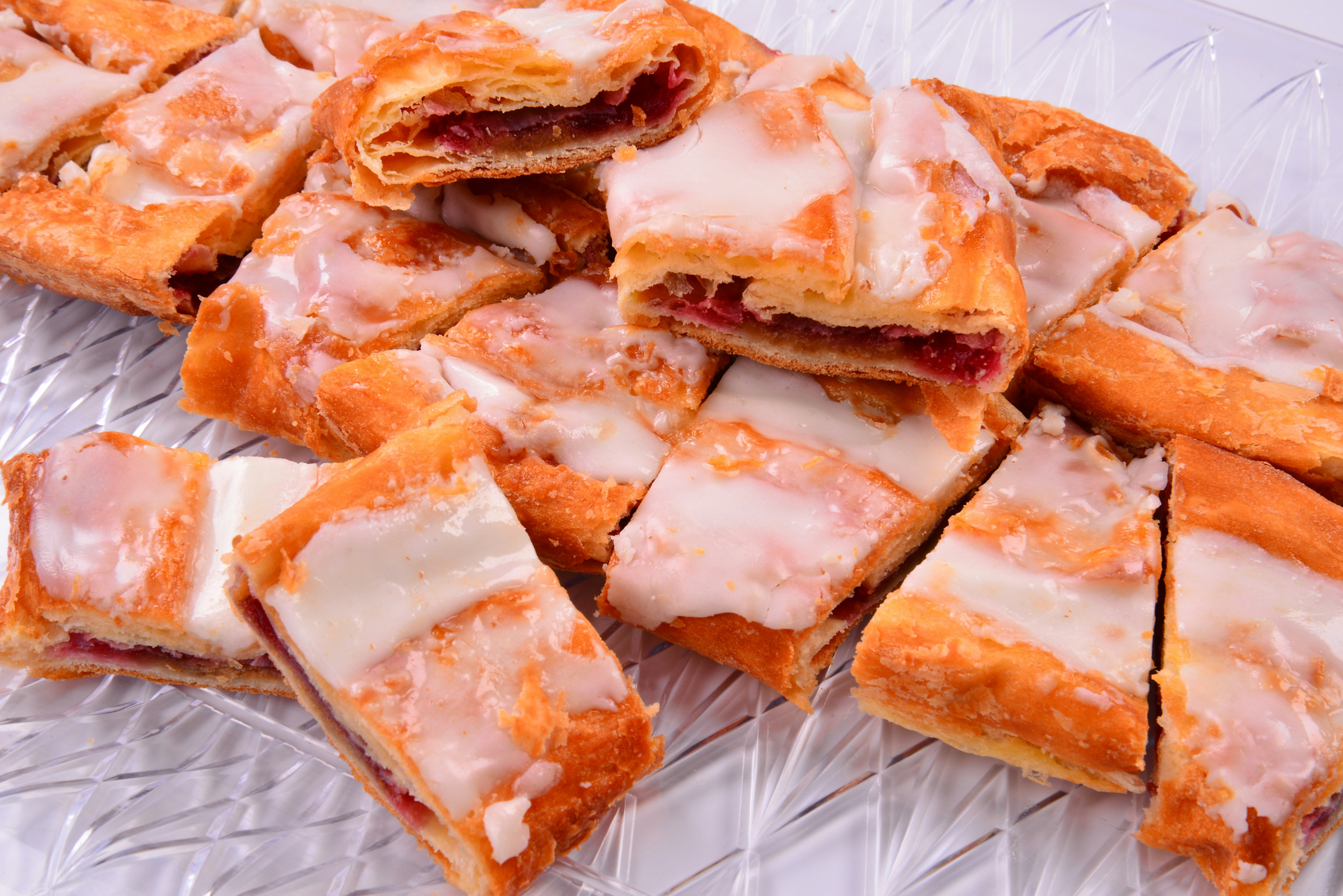 A light and flaky Danish pecan kringle smoothered in ice sugar on a glass plate in Racine, Wisconsin