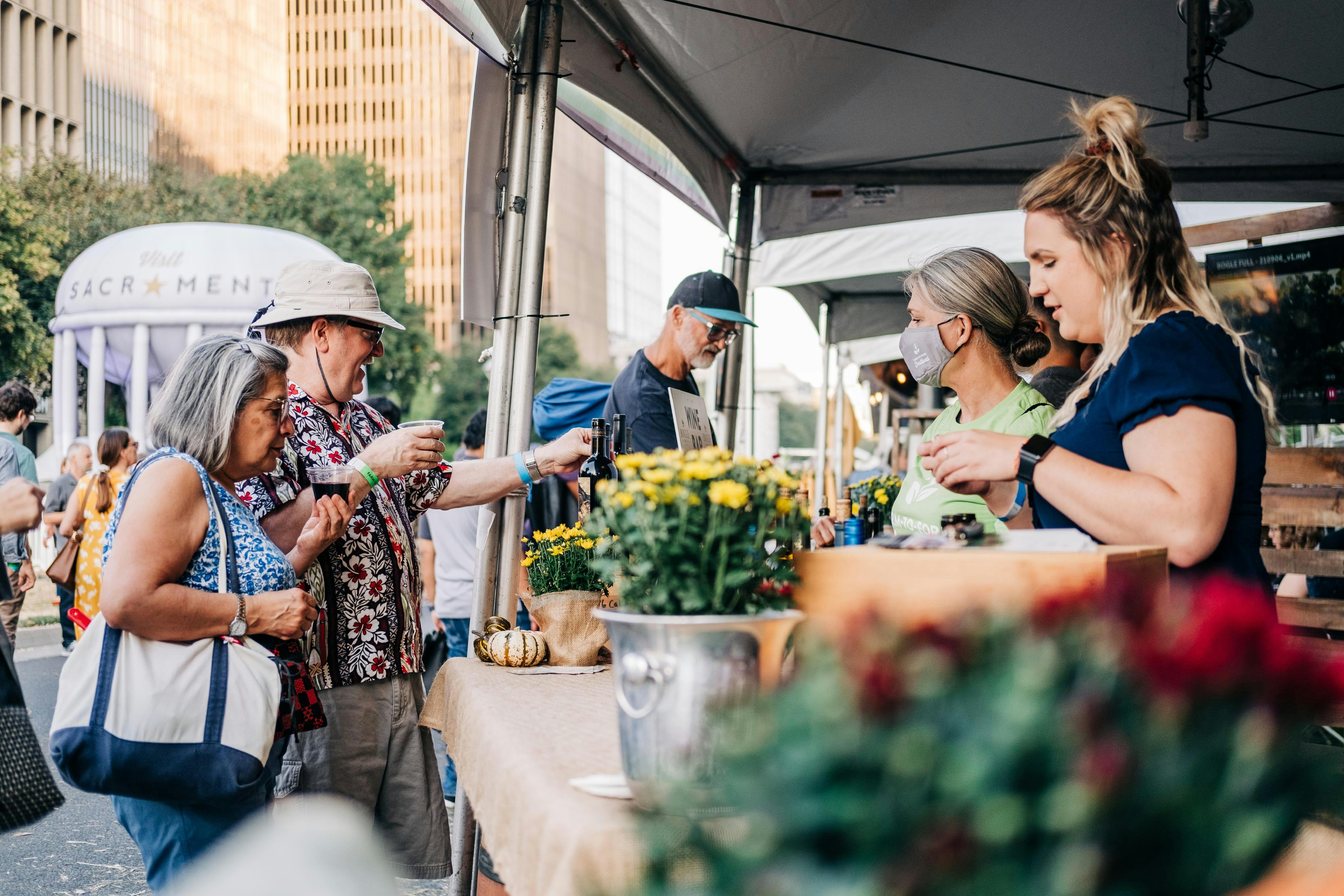 People at a tent at Sacramento's 2021 Farm to Fork Festival, held on the Capitol Mall featuring food vendors, live music, demo stages, and more