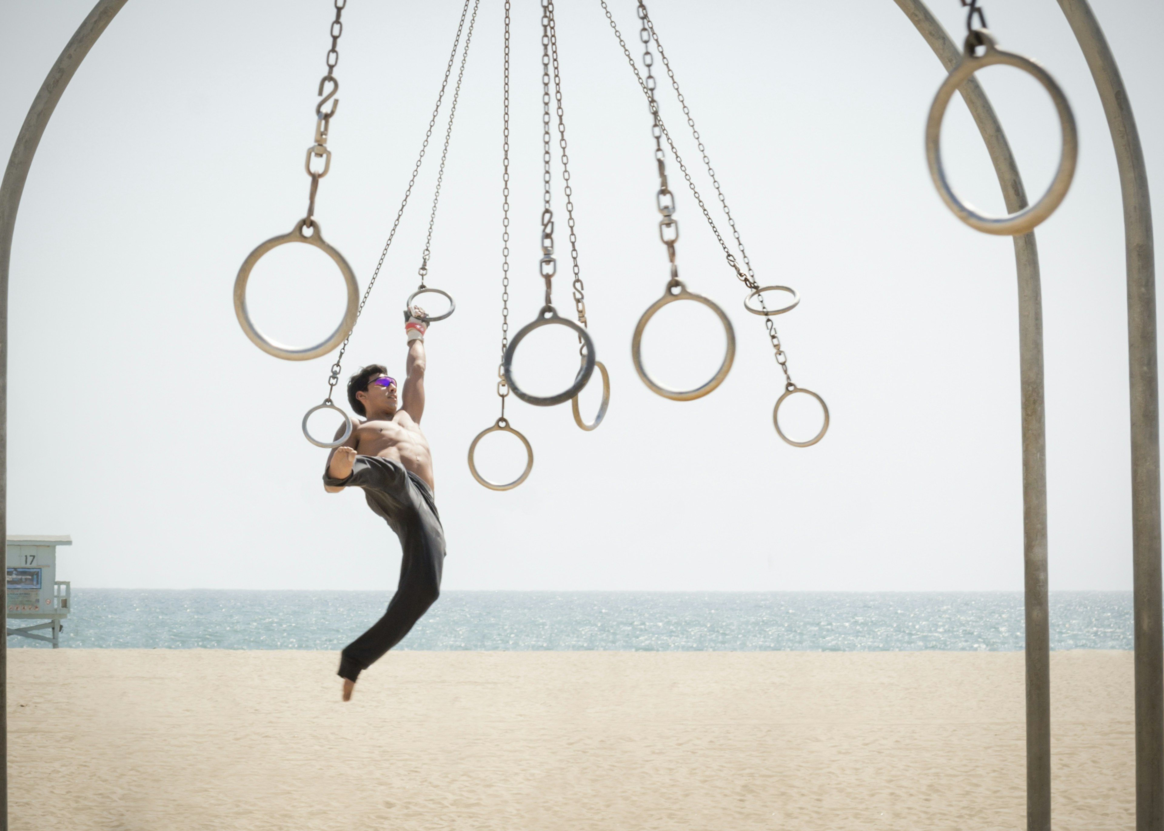 Man swings on suspended rings at an outside gym near Santa Monica beach