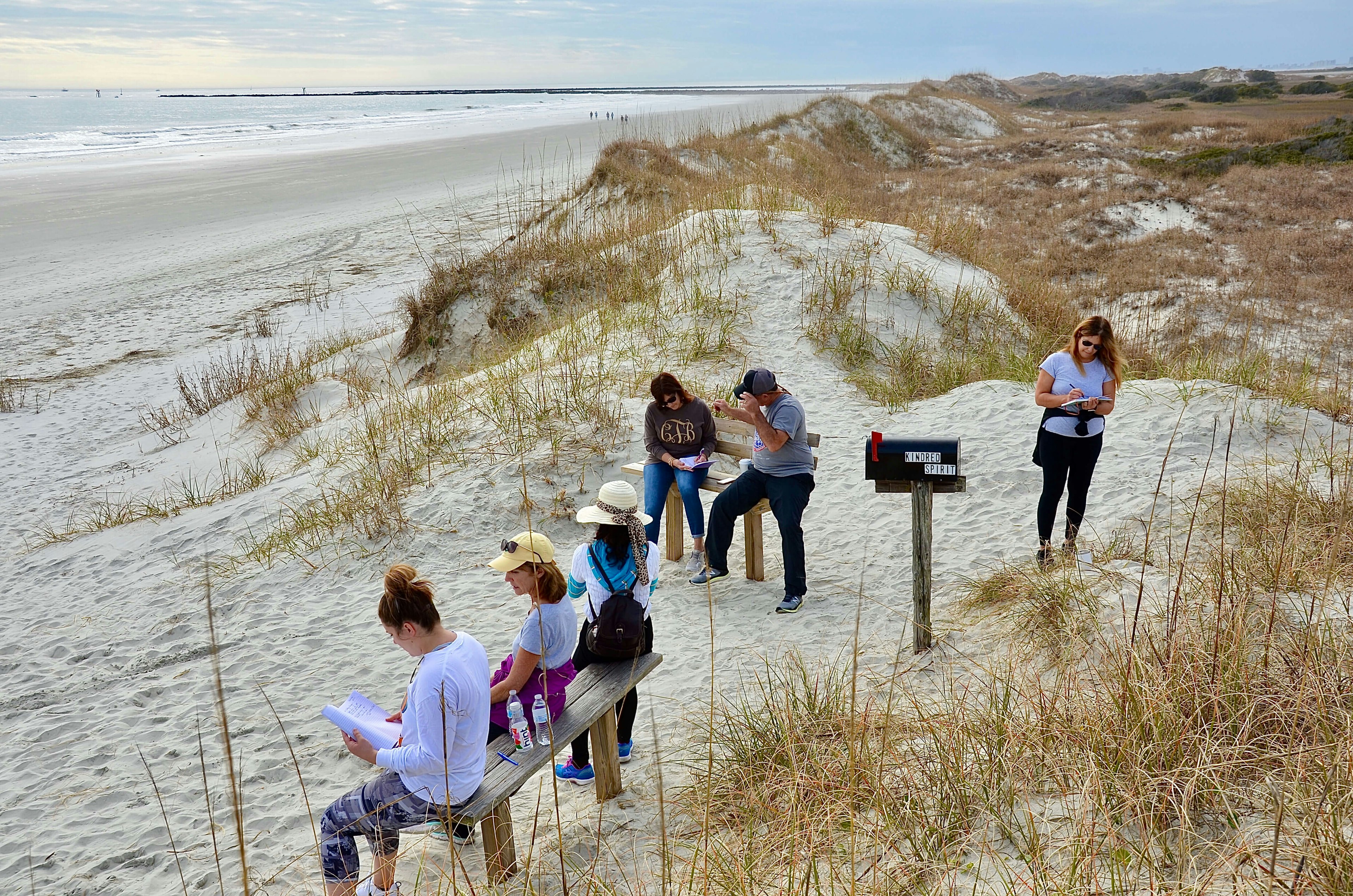 Group of people gathering around Kindred Spirit Mailbox, a unique landmark on the Sunset Beach, to write down their stories or secrets as spiritual release