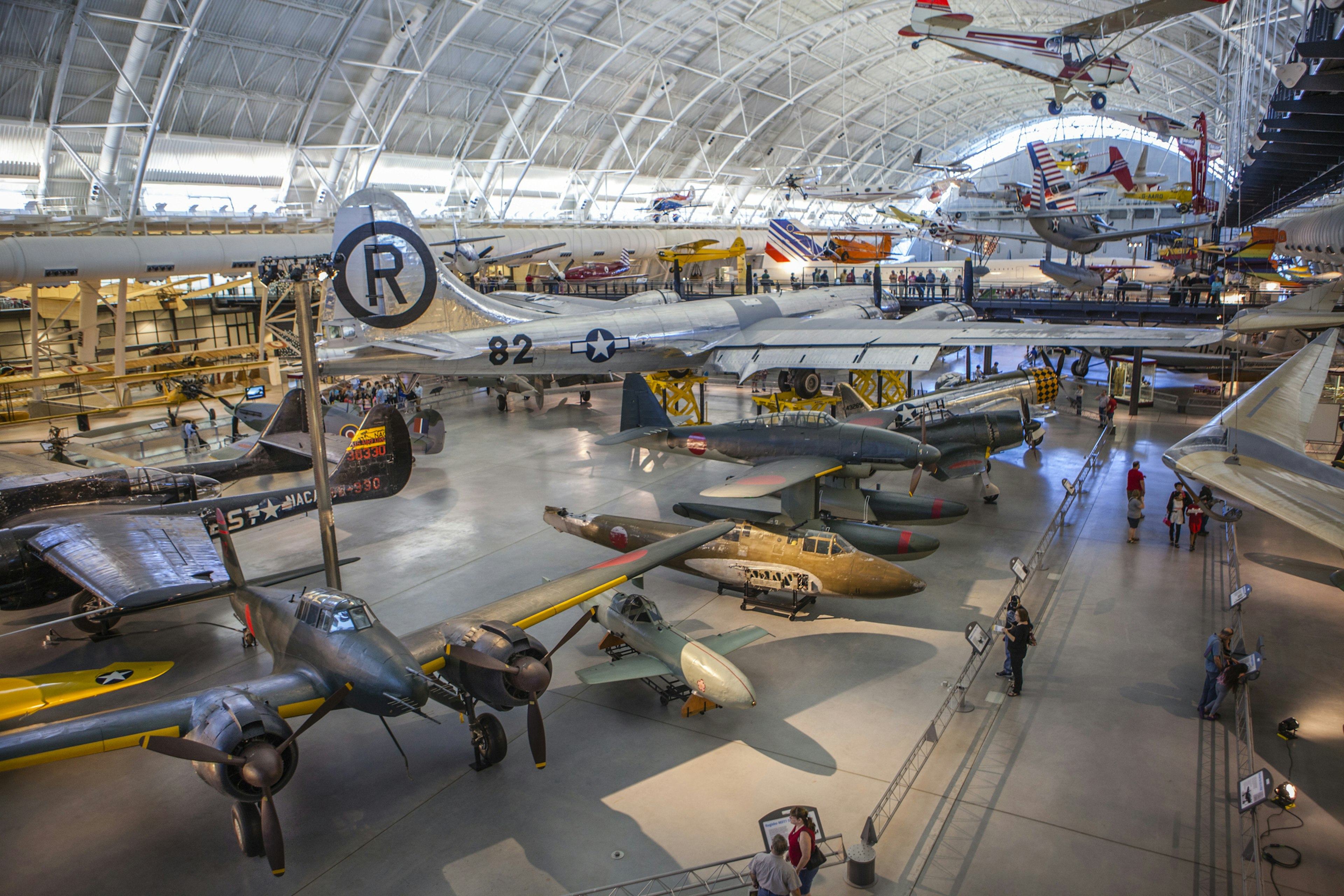 A huge aircraft hangar displaying many different types of plane, rocket and engine. People are following the walkways between exhibits