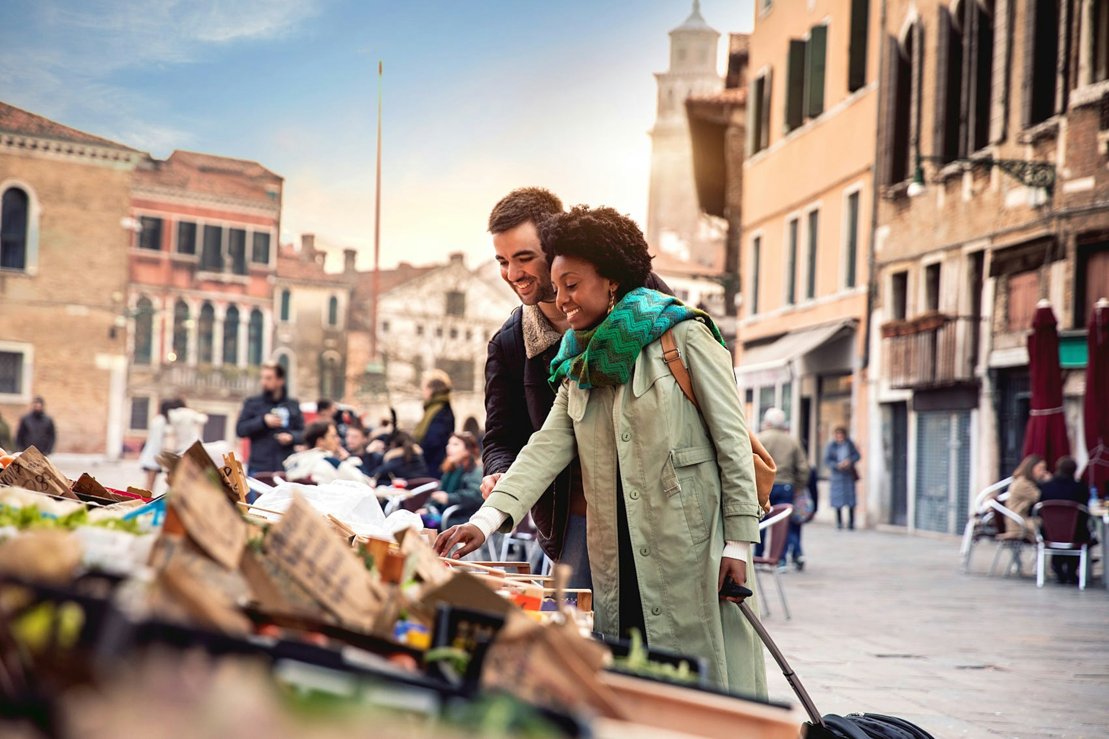 A woman and man shop at a stall in historic Venice.