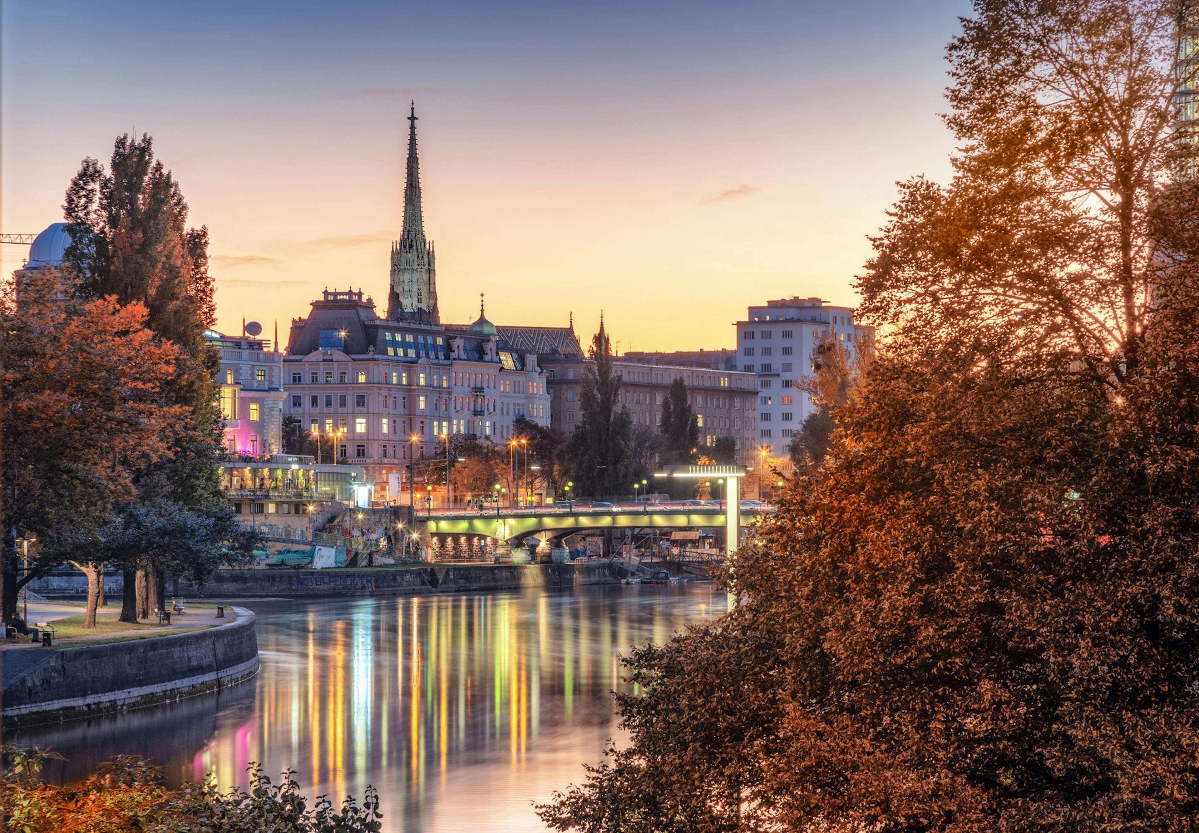 View of Vienna, evening city lights reflecting in Danube canal and temple of St. Stephen's Cathedral from Leopoldstadt district late autumn sunset