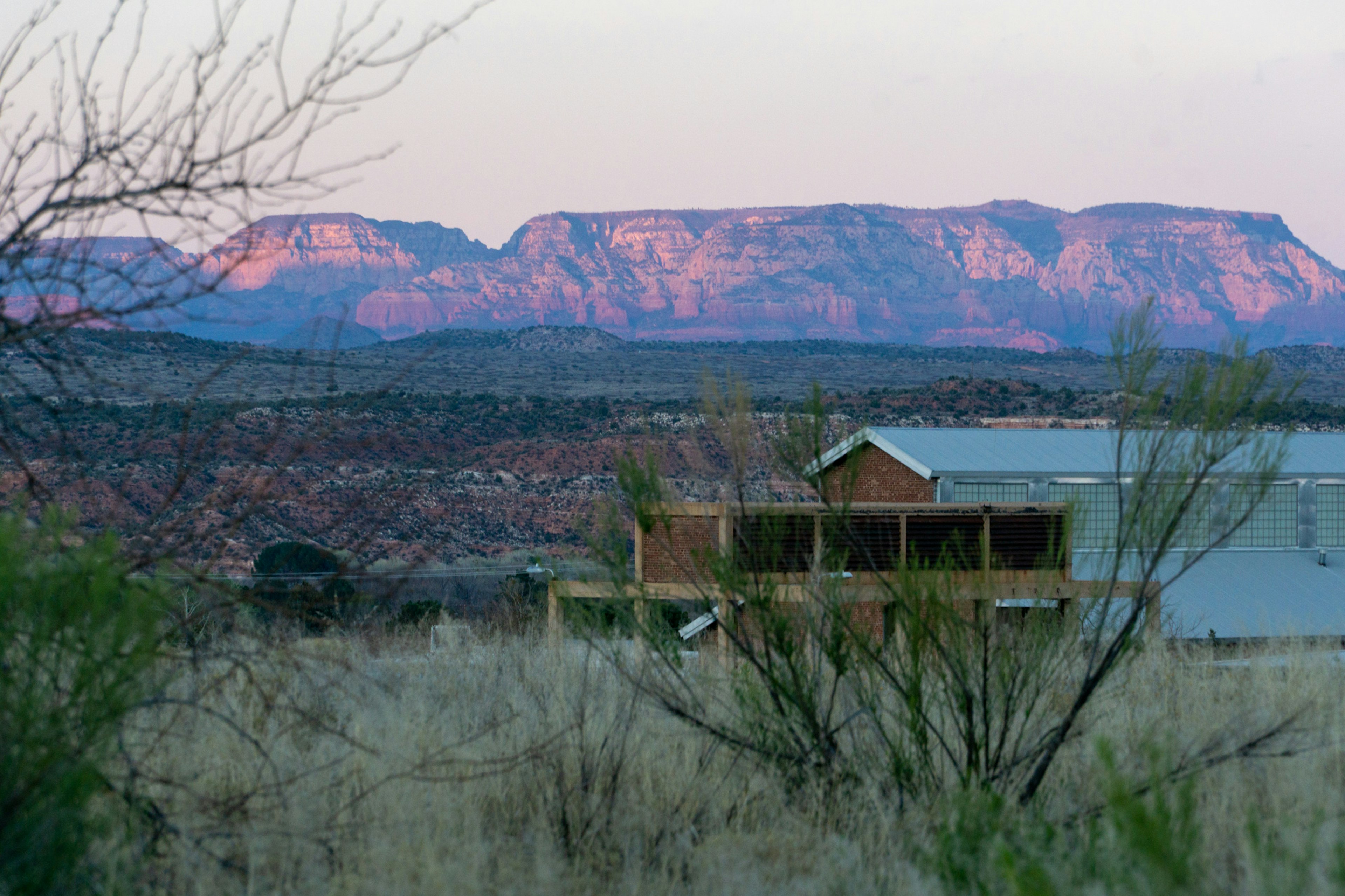 A view across countryside towards distant hillsides that glow red in the sunlight