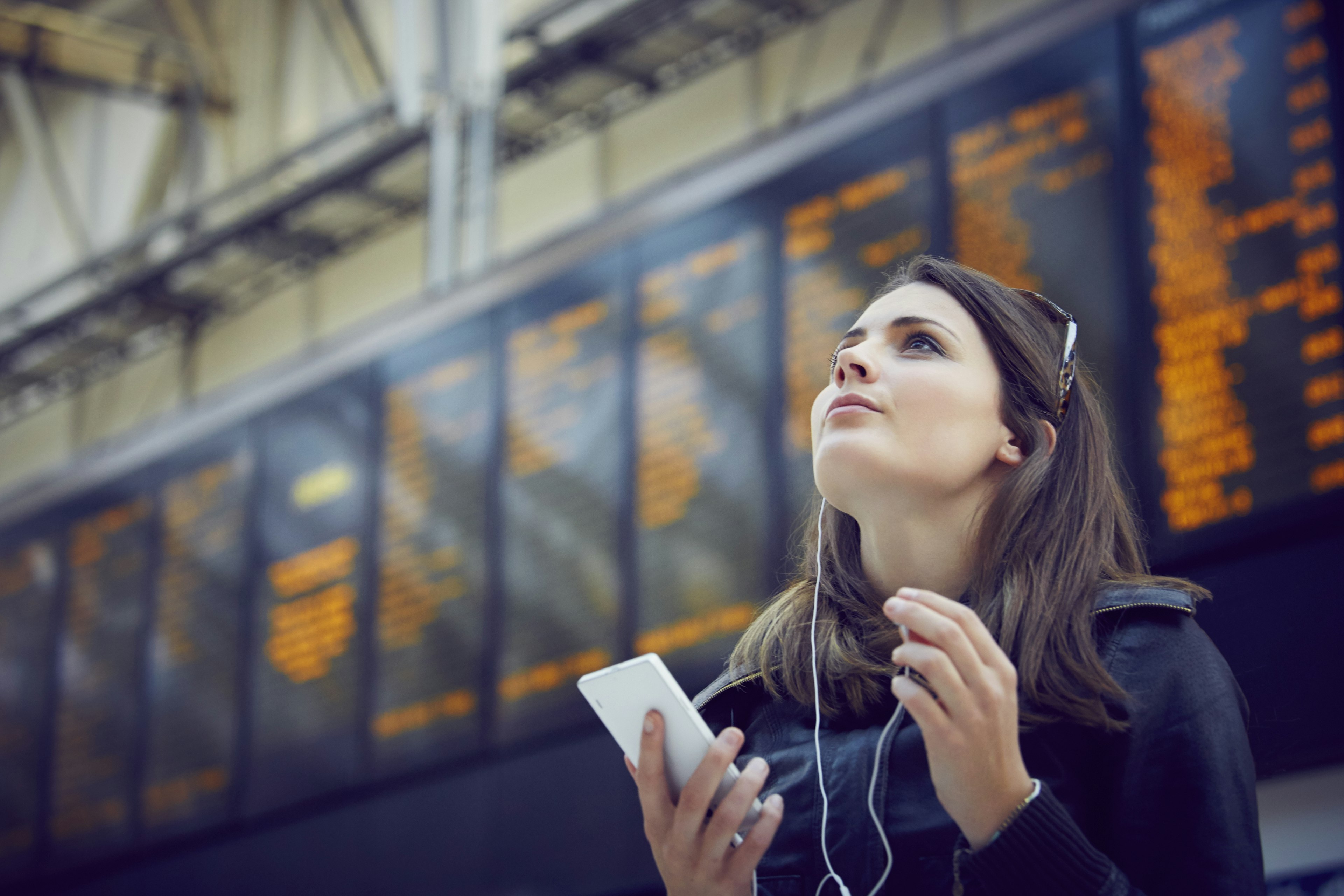 Woman looking at departure information, London, UK