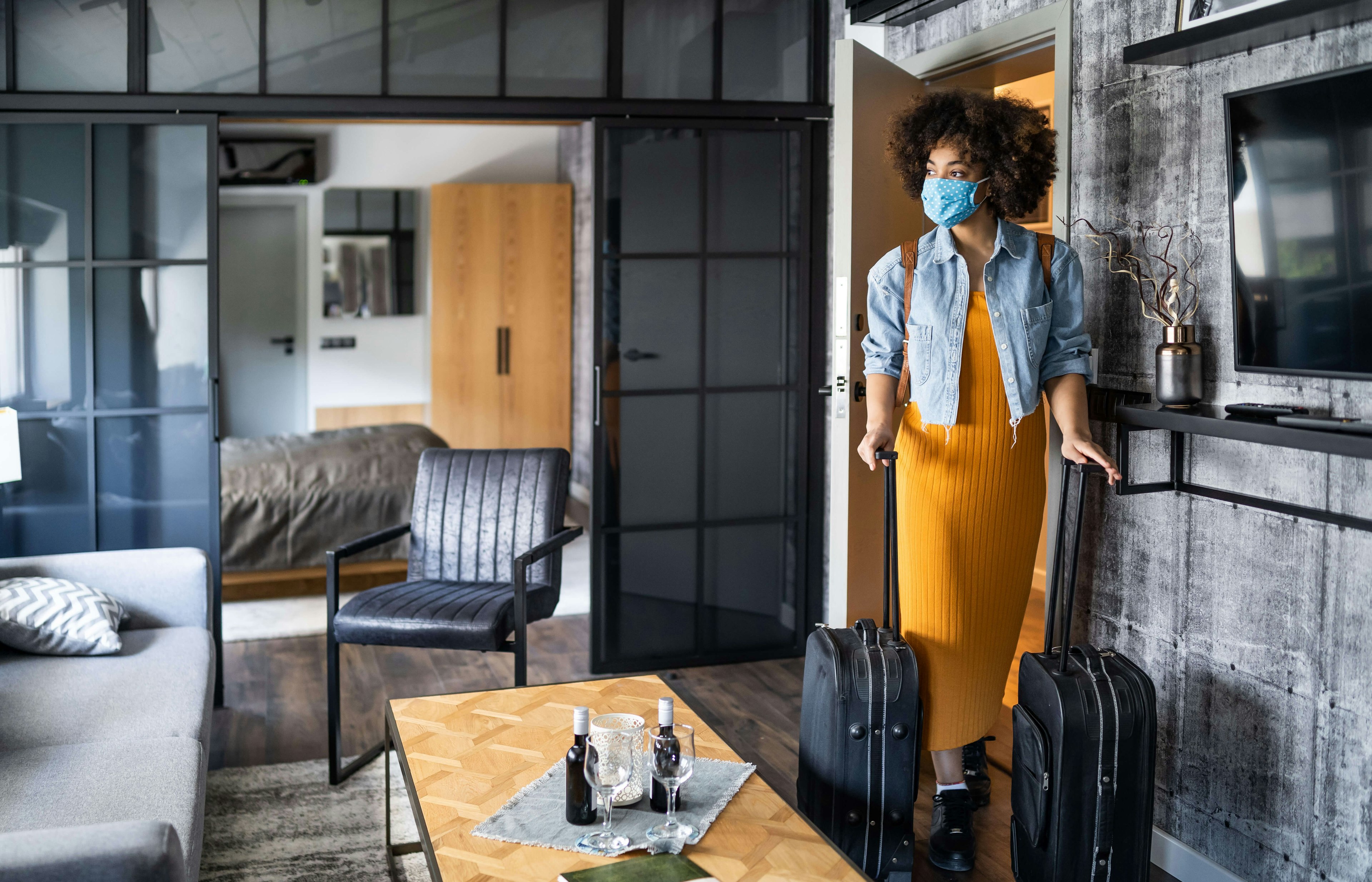 Woman with protective face mask arriving in hotel room.