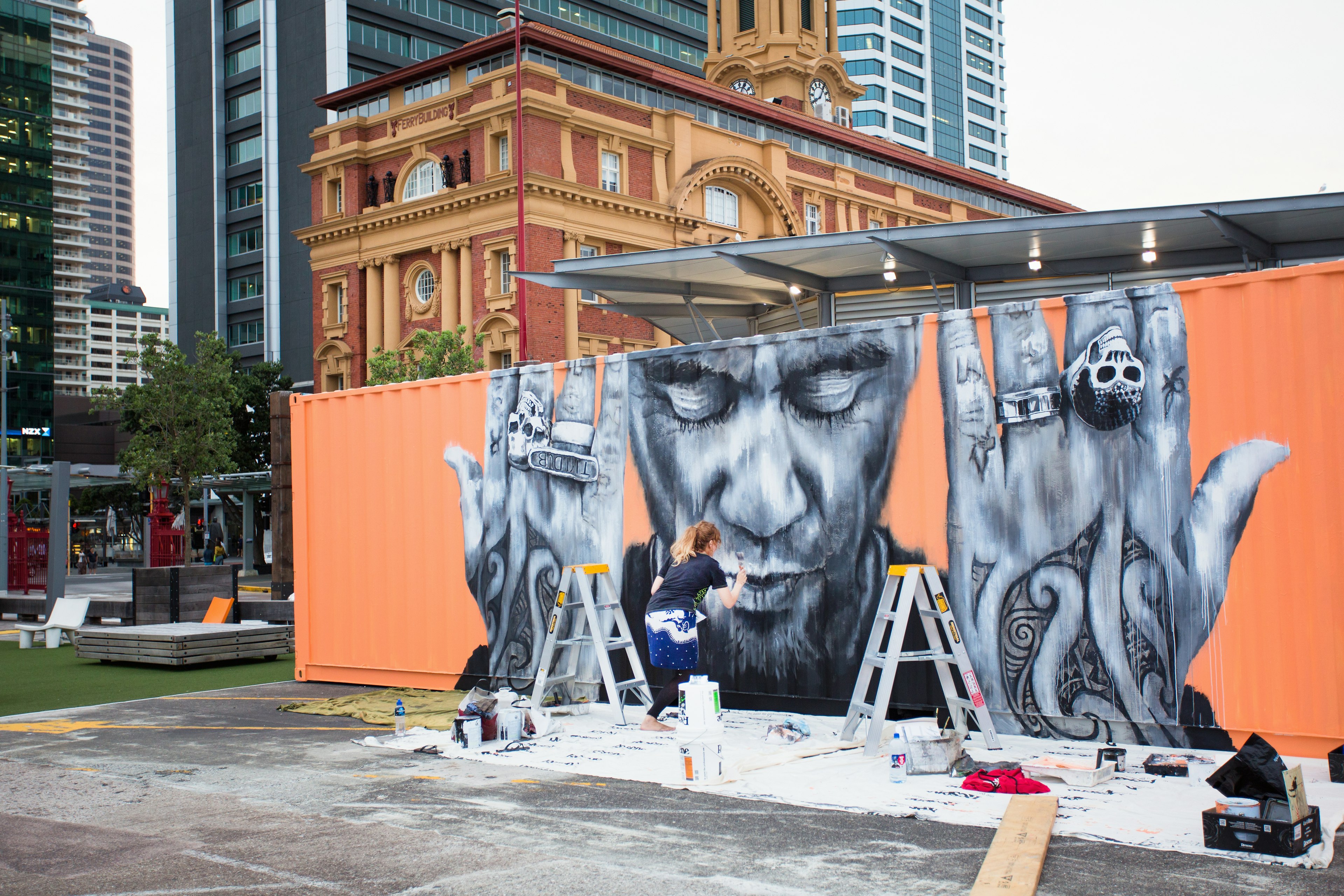 An artist creates a mural on a boxcar.