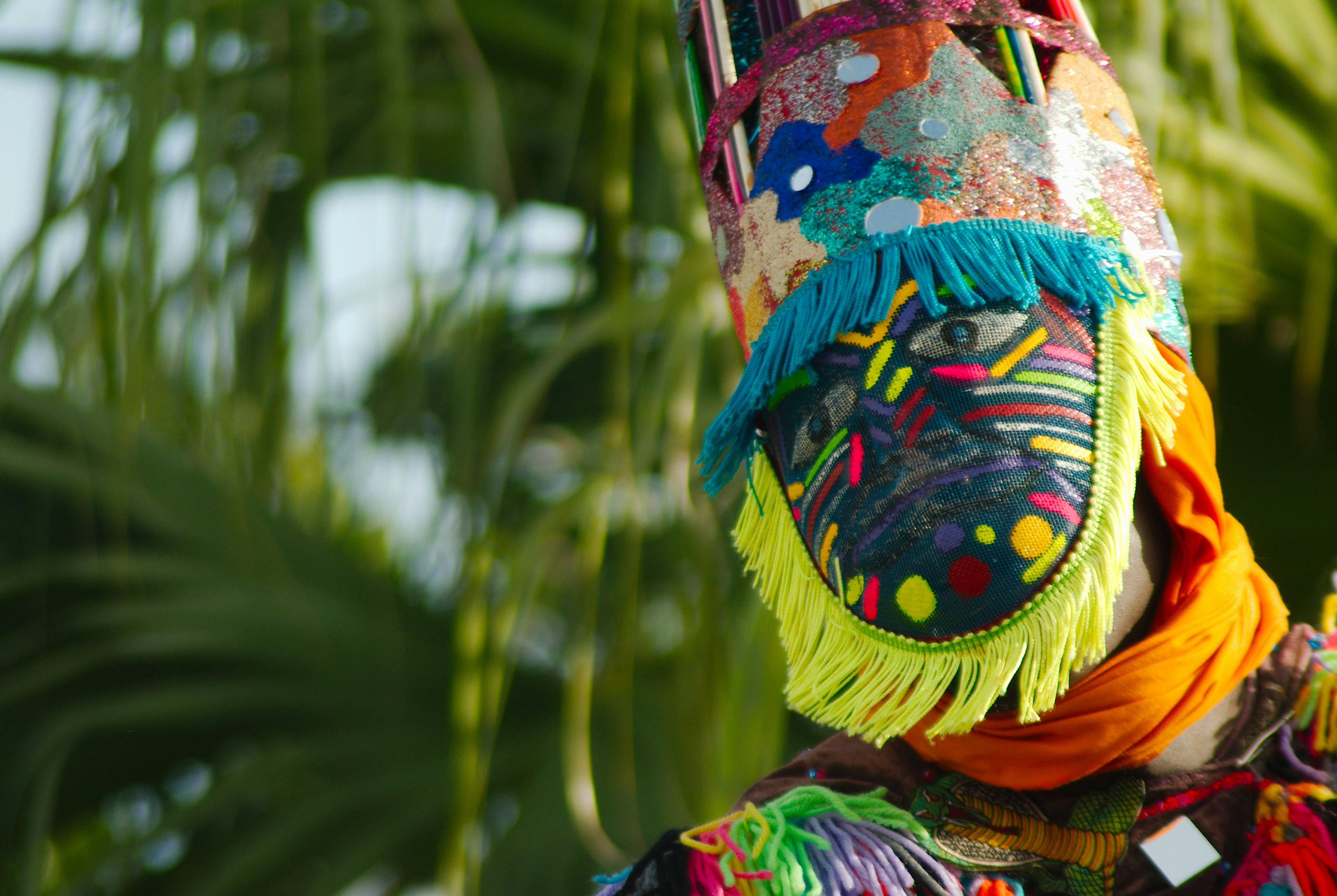 A masked figure wearing a colorful head dress