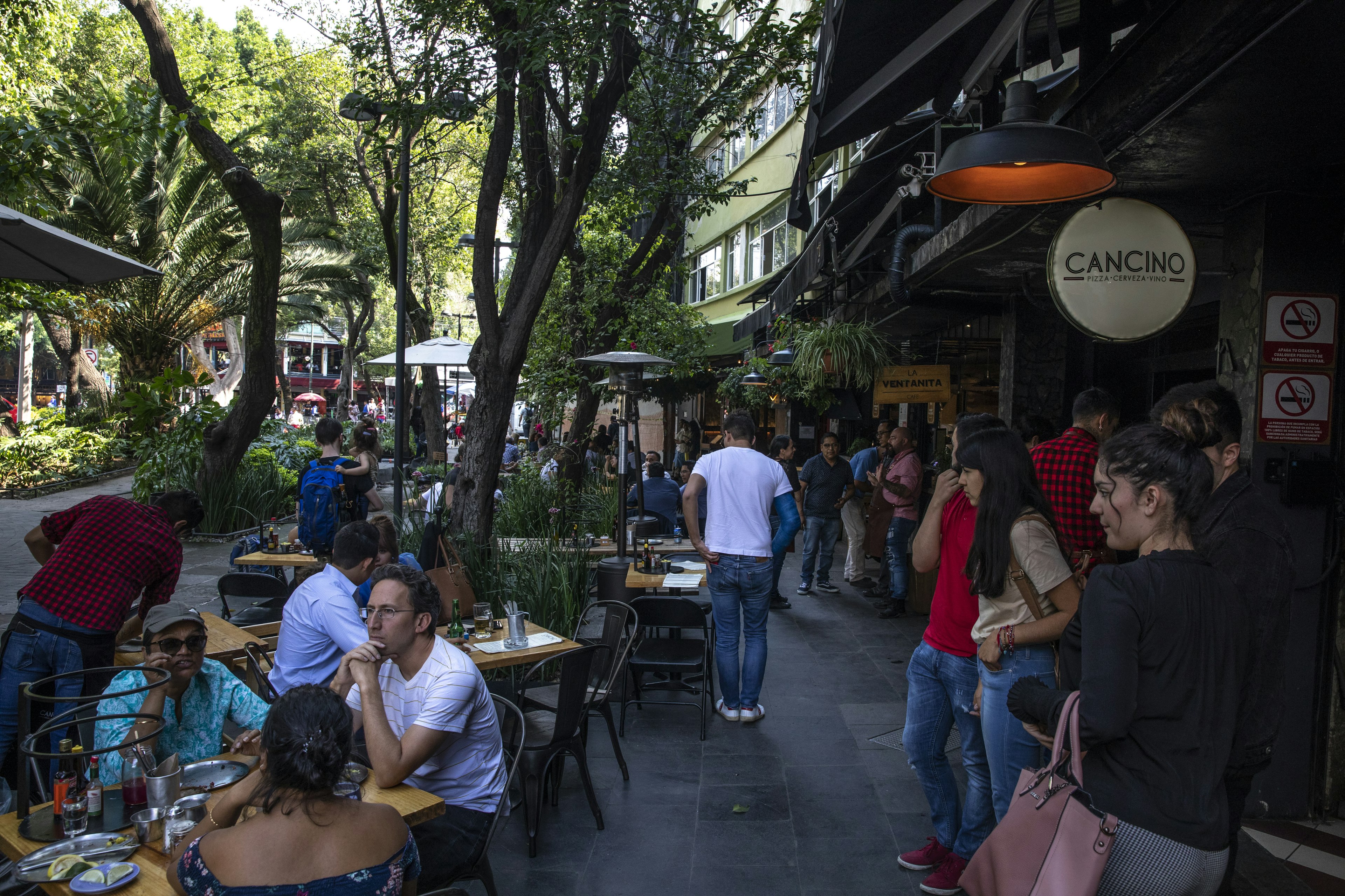 People dining at streetside tables at a restaurant in the Mexico City neighborhood of Roma