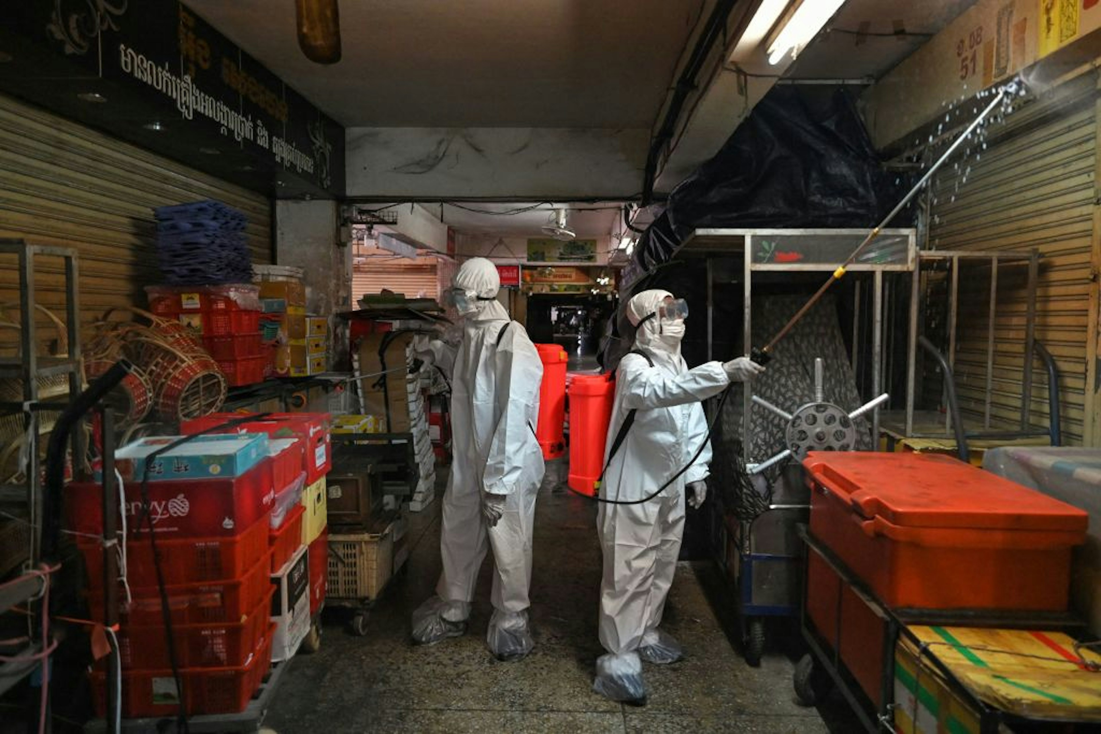 Workers wearing personal protective equipment (PPE) spray disinfectant in the Orussey market, after it was temporarily closed following a few vendors testing positive for the Covid-19 coronavirus, in Phnom Penh on April 4, 2021.