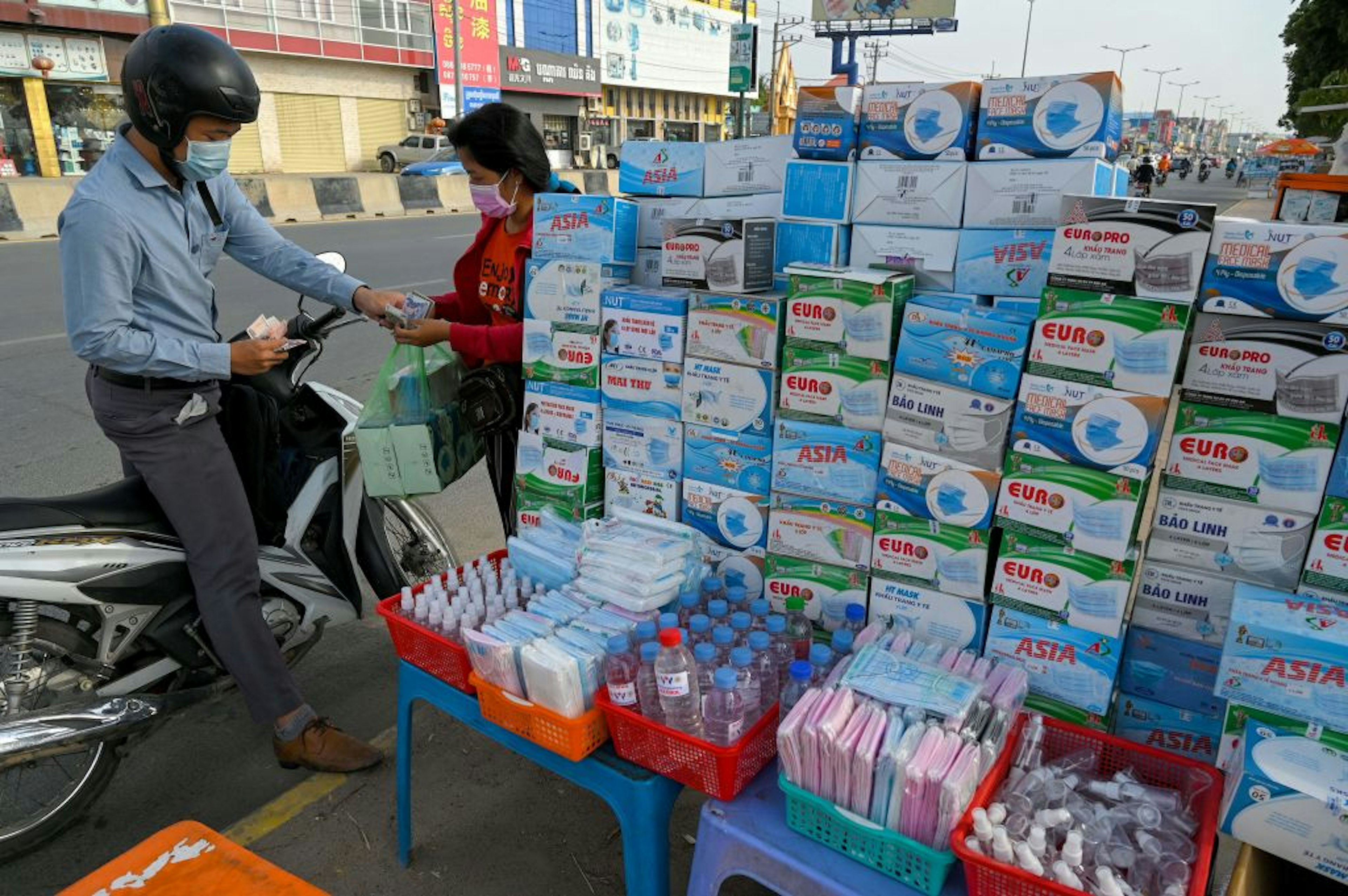 A motorist buys face masks from a vendor along a street in Phnom Penh on March 31, 2021.