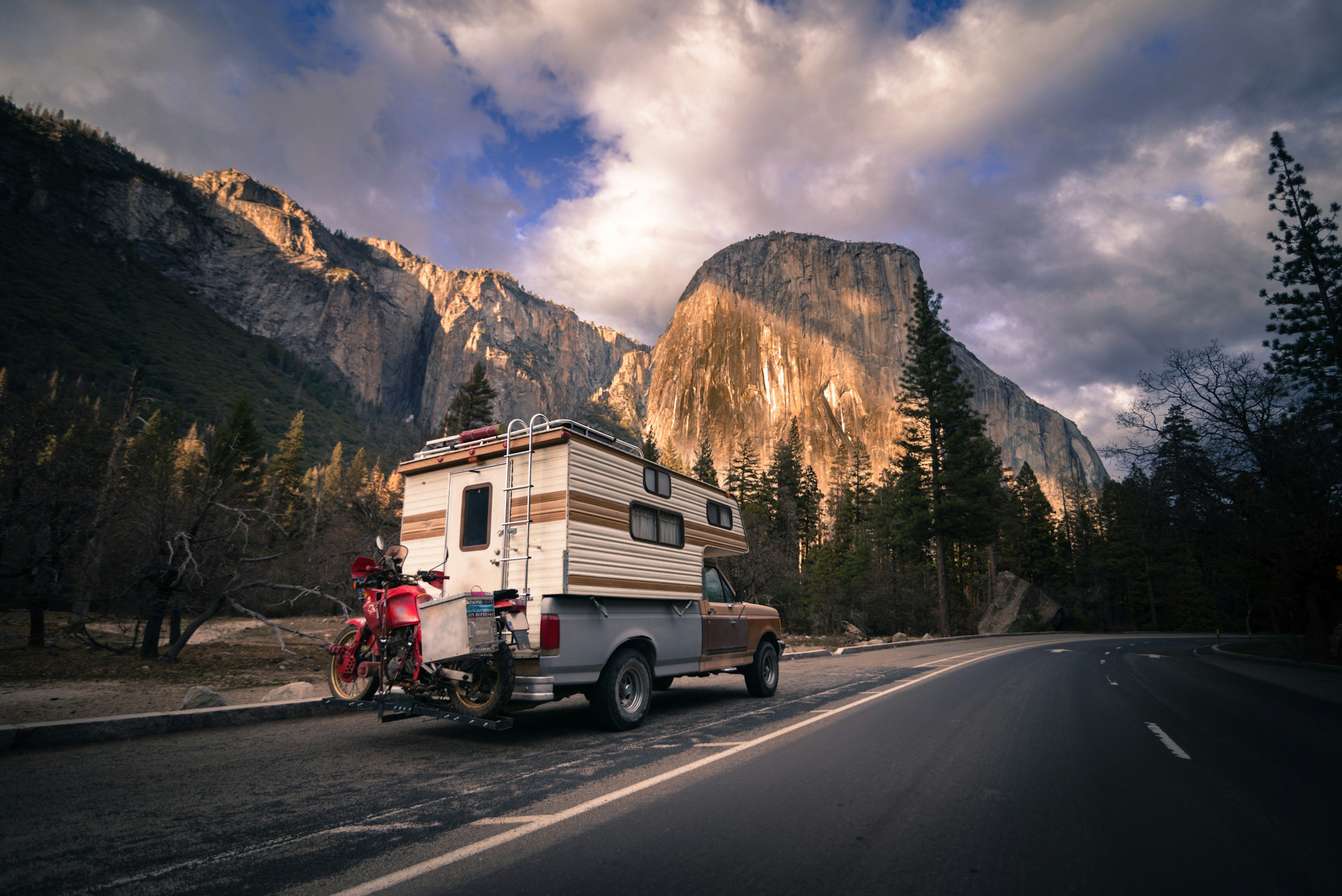 RV with bikes attached, driving down a road