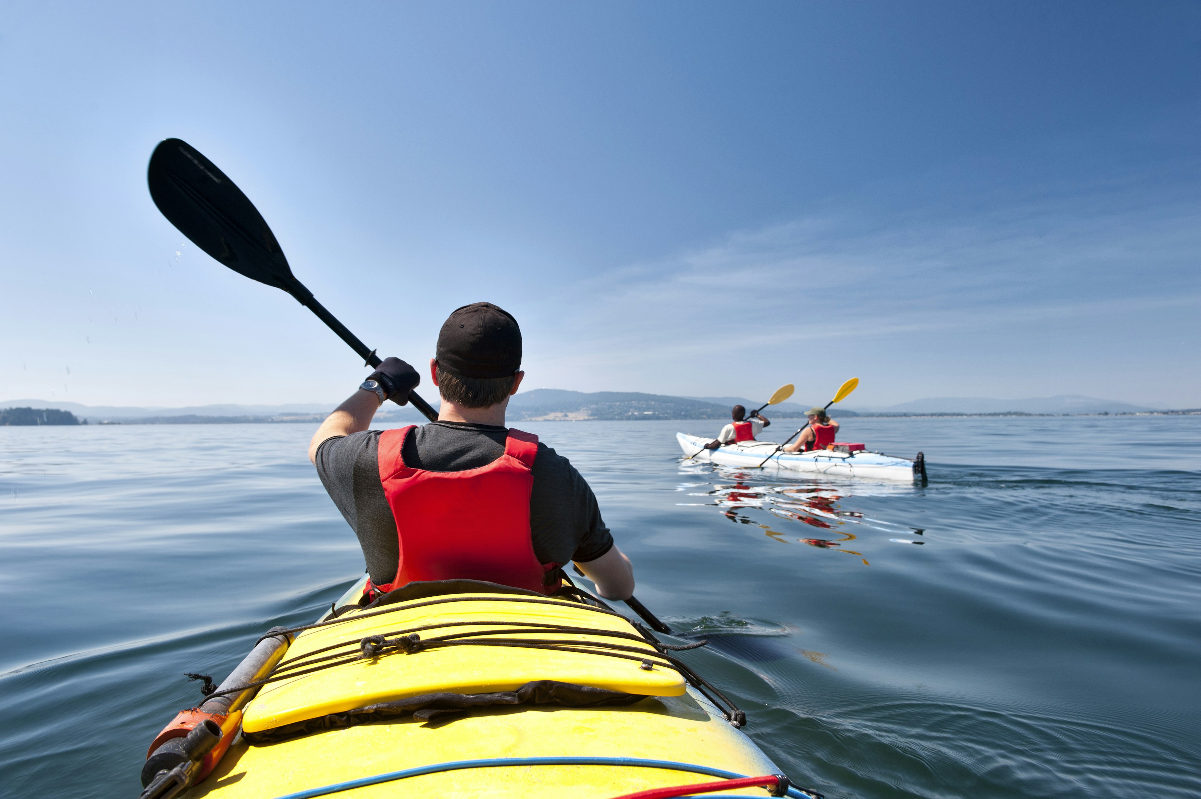 A kayaker in a yellow kayak paddles along still waters