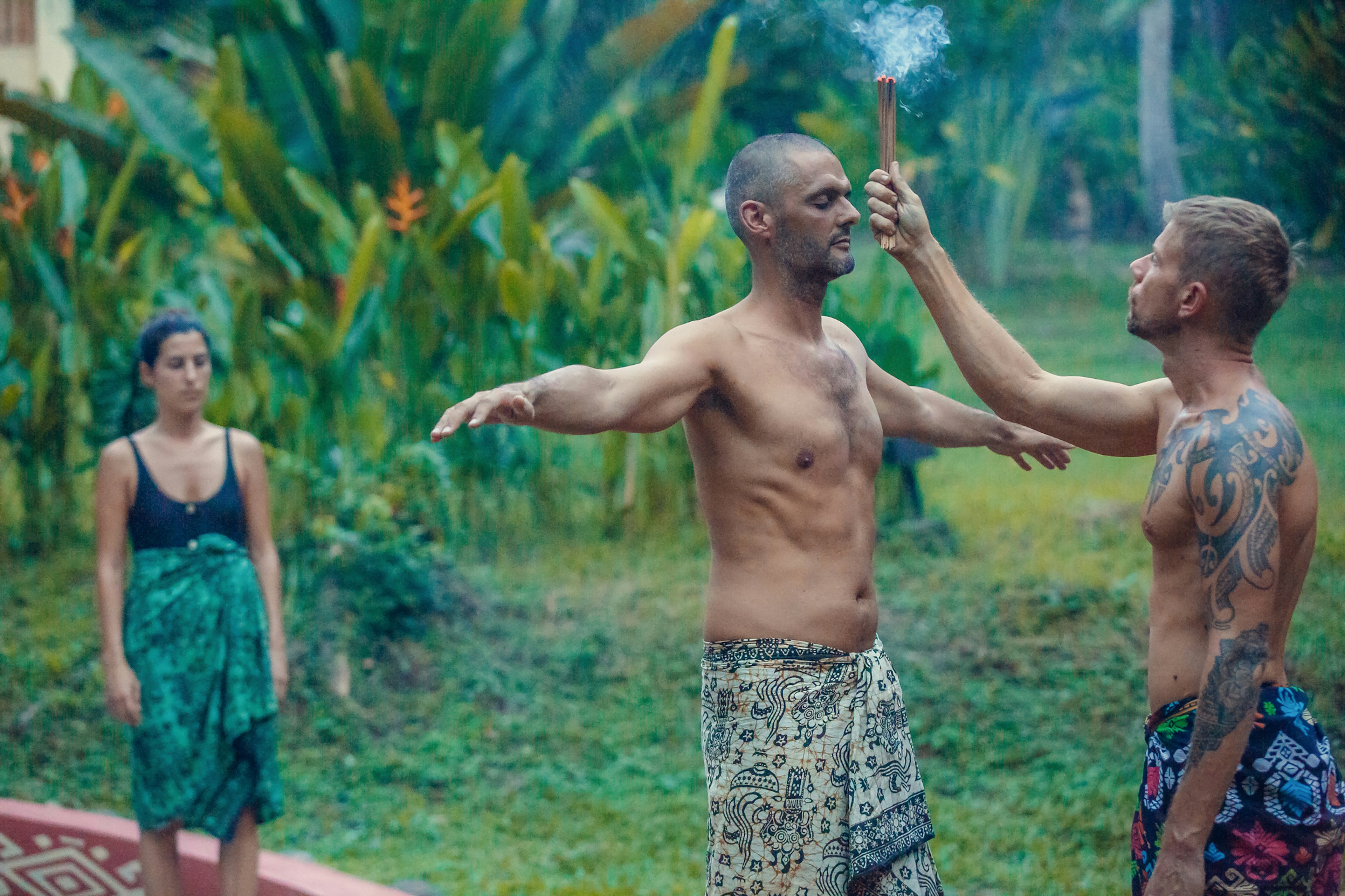 A man stands in front of a shaman in a jungle setting while smoke is wafted over his head during a temascal ceremony in Mexico