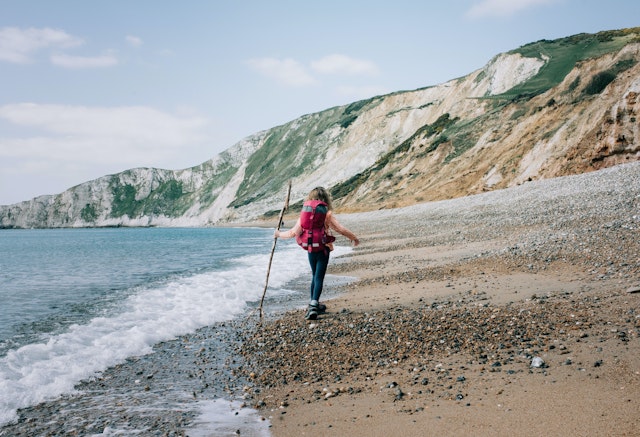 girl walking along the Jurassic coast with a stick on a beautiful day