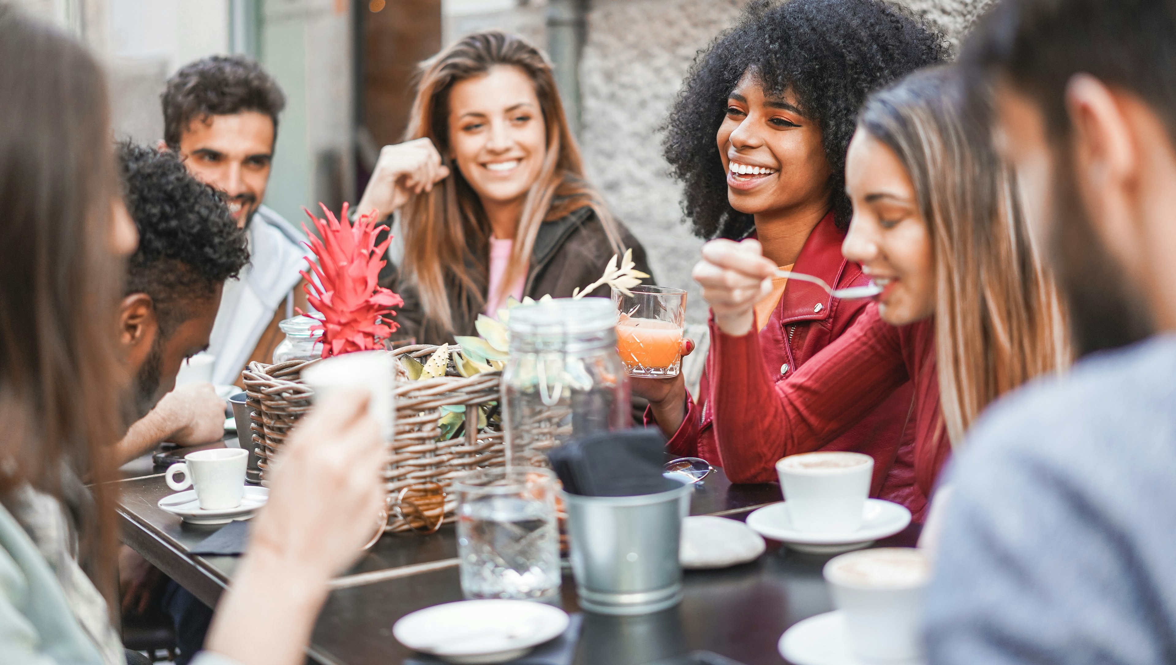 Group of happy friends drinking coffee and cappuccino at a bar outdoors in Italy