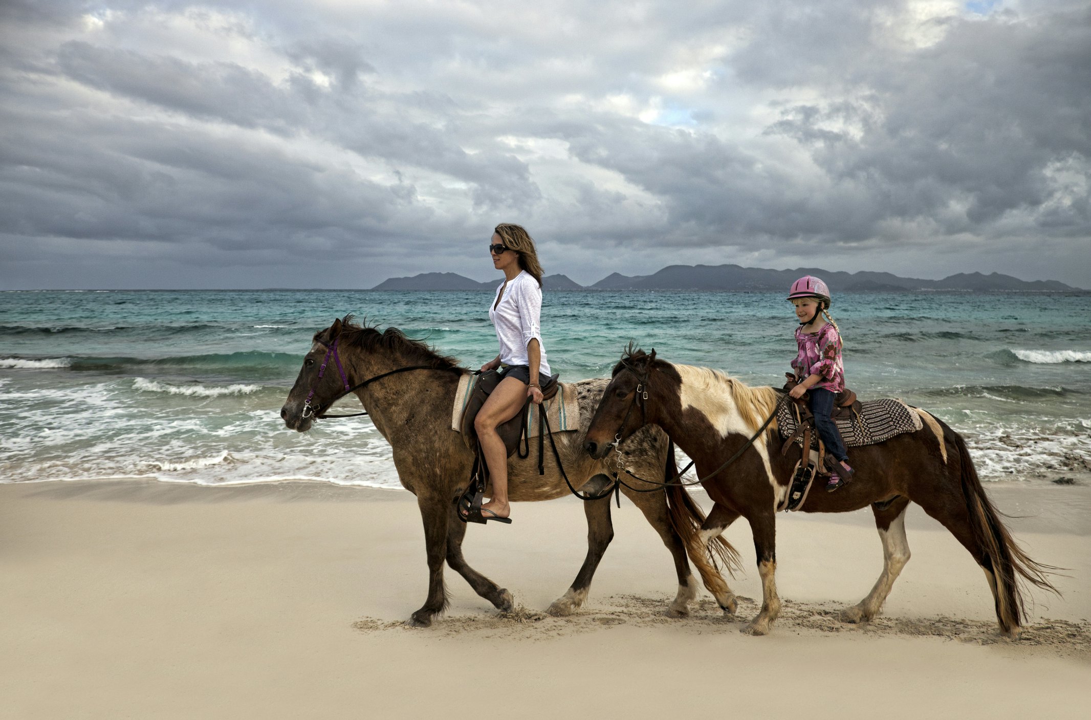 Mother and daughter riding horses on a beach in Anguilla