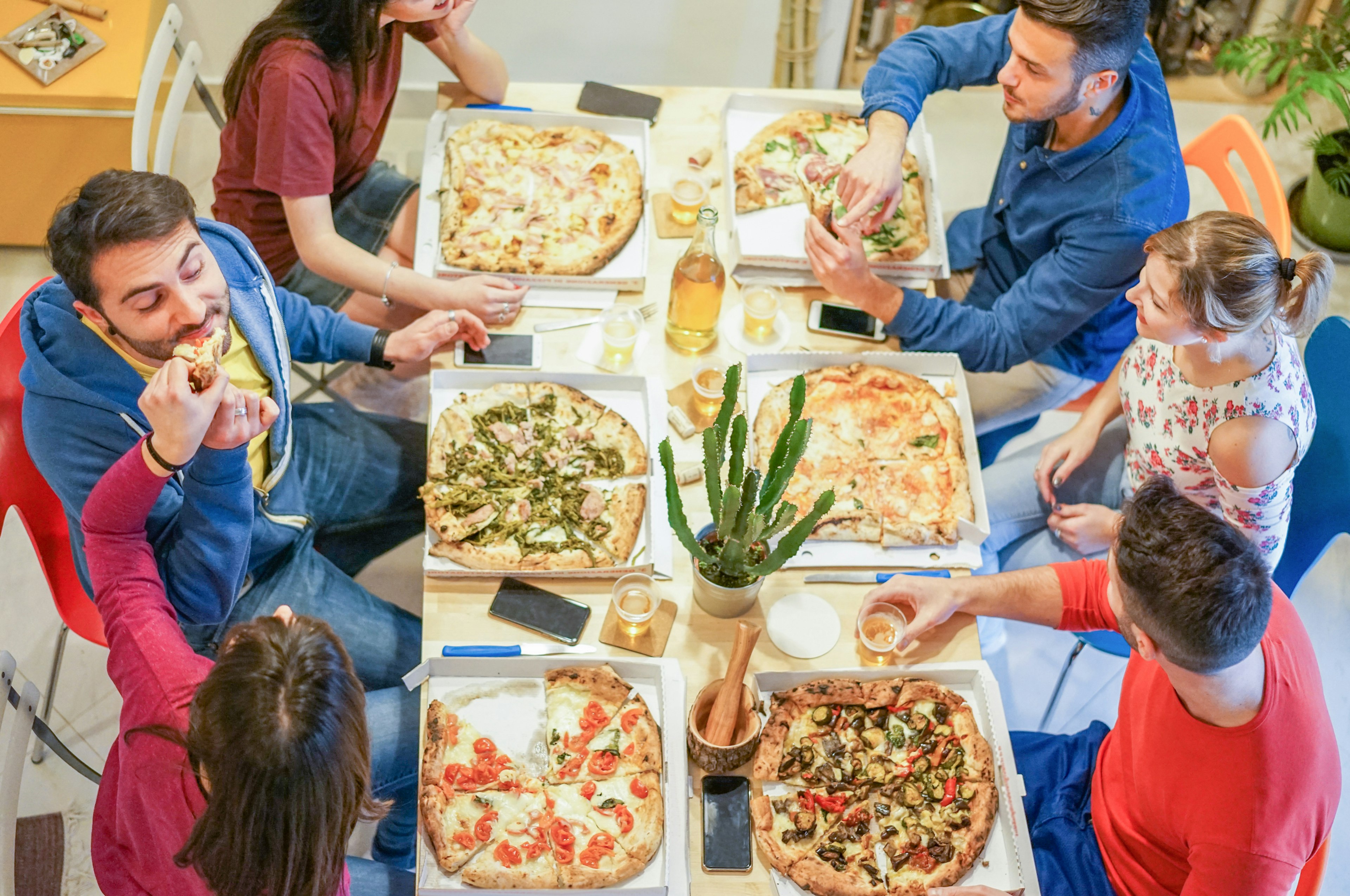 A group of friends around a table, eating pizza and drinking beer