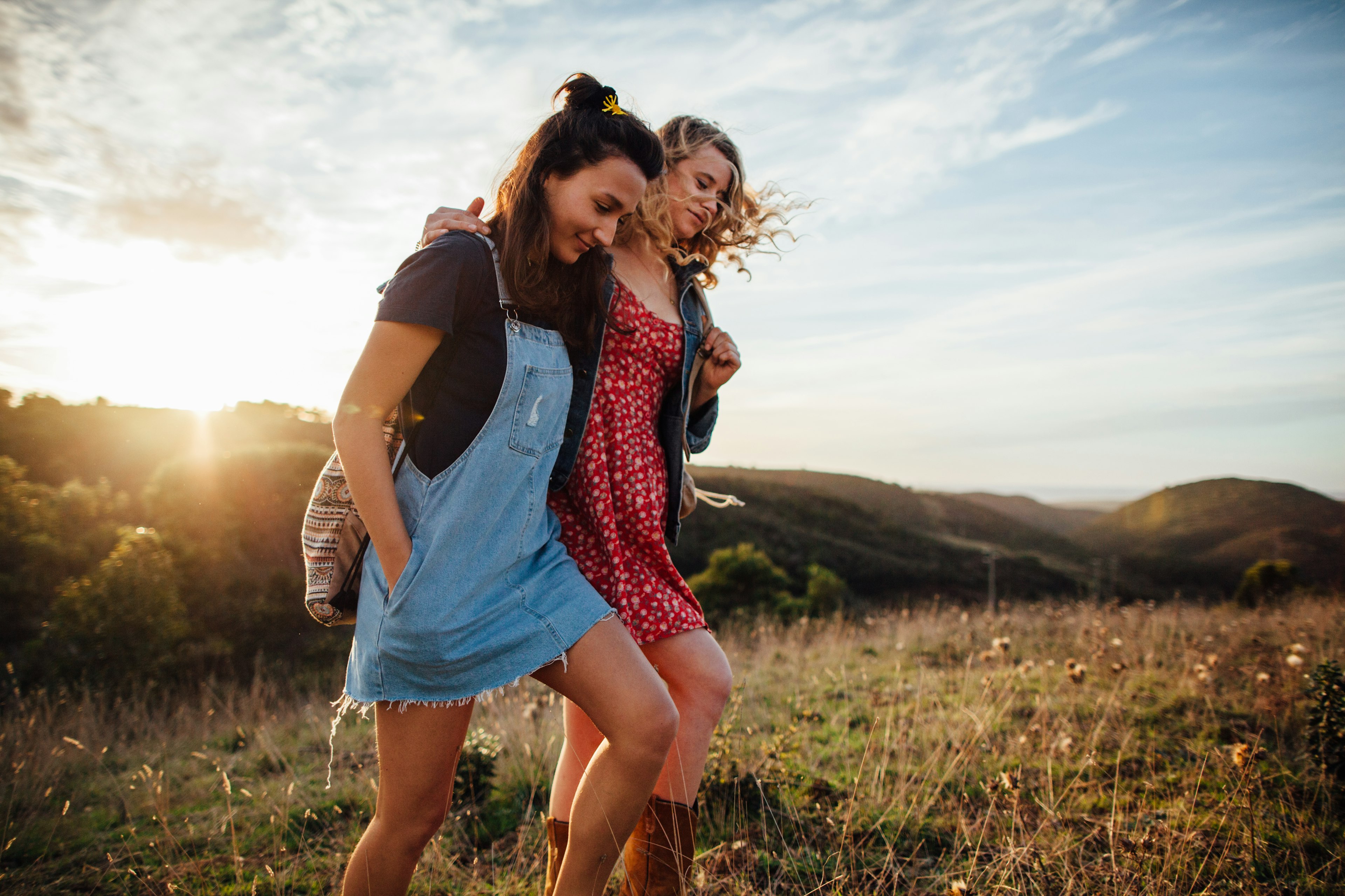 Two young women walking together in sunshine.