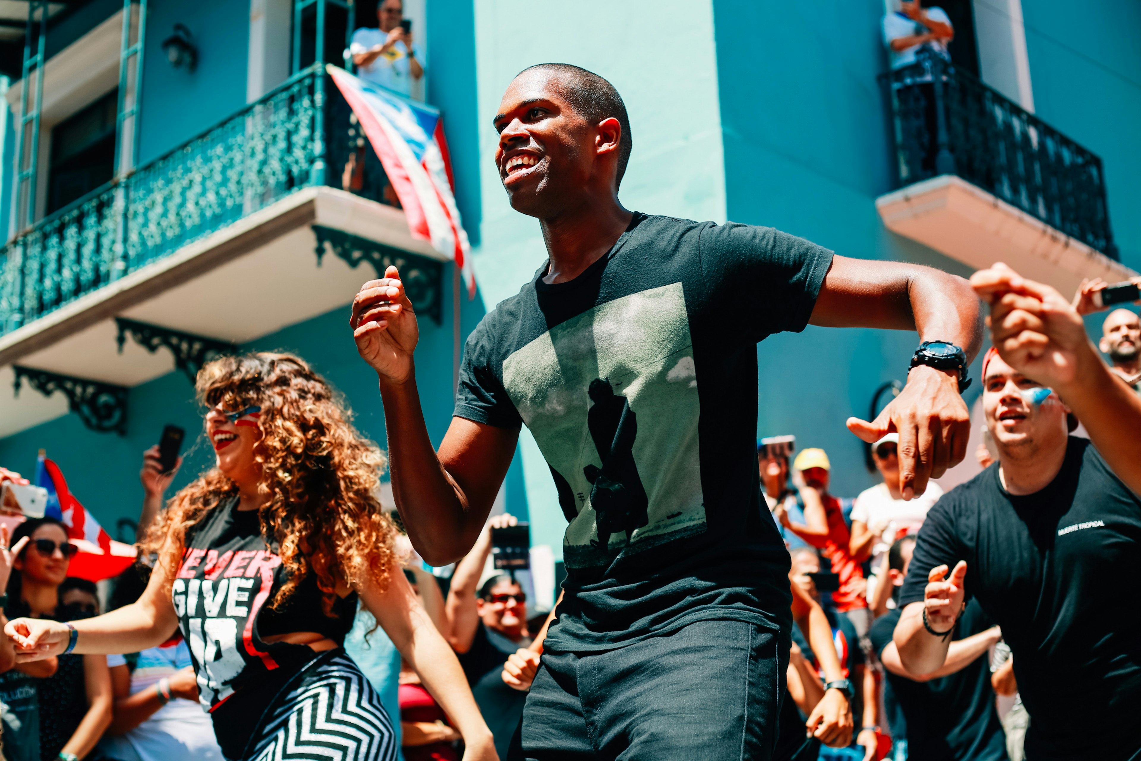 A man smiles as dances to salsa music alongside a group of people in Puerto Rico.