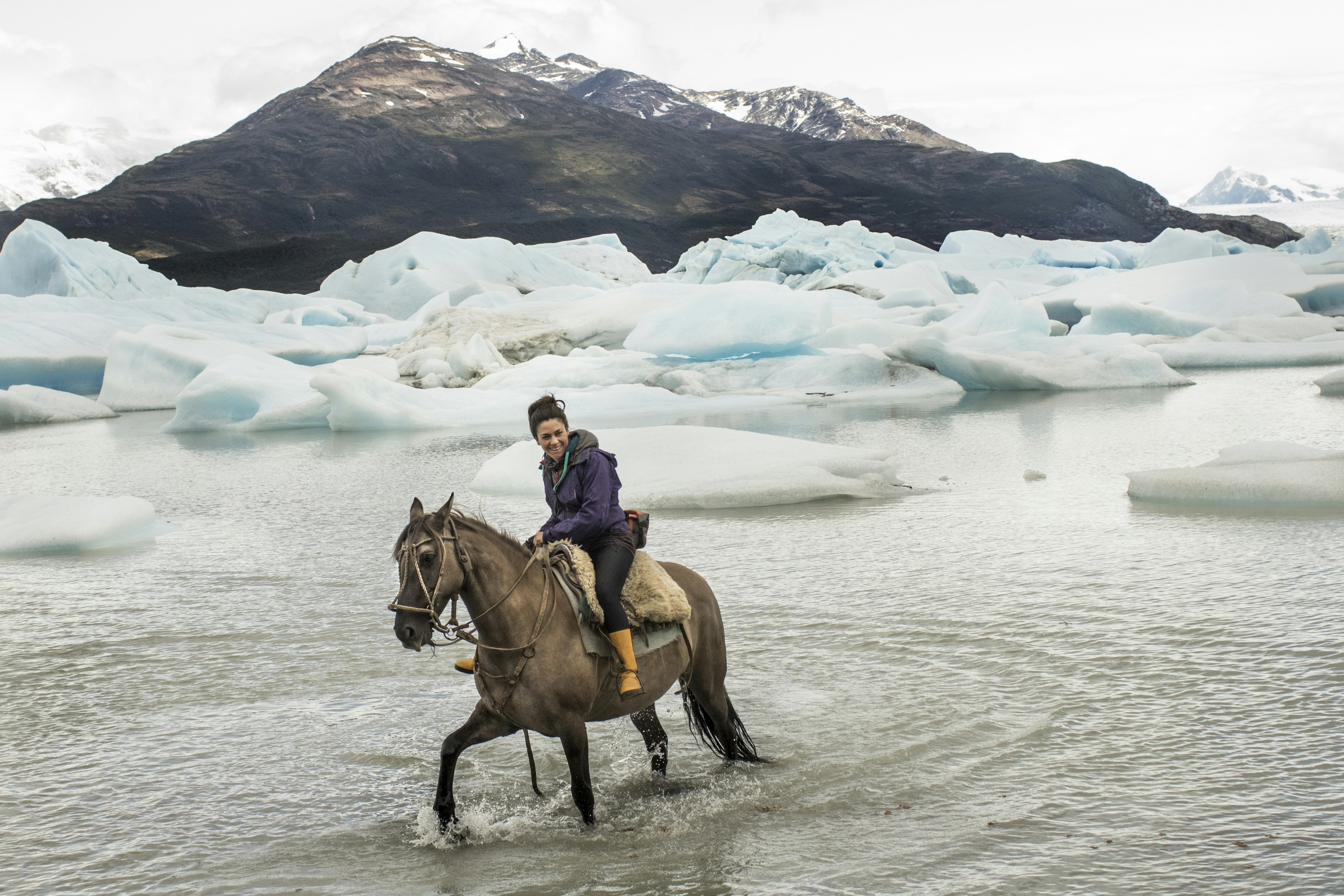 Chilean woman rides a horse in glacial lake