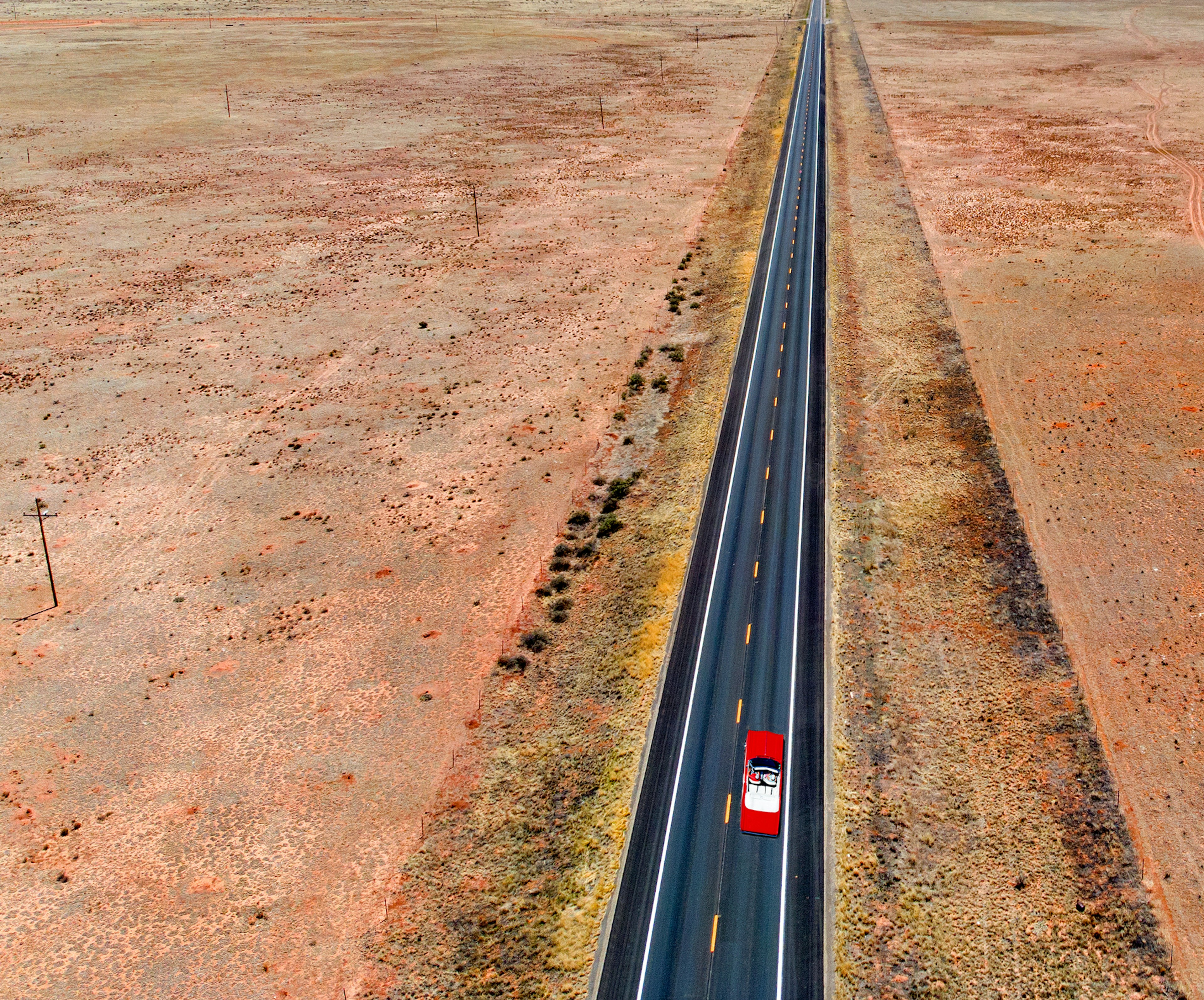 Red car driving down Route 66 in Arizona surrounded by desert