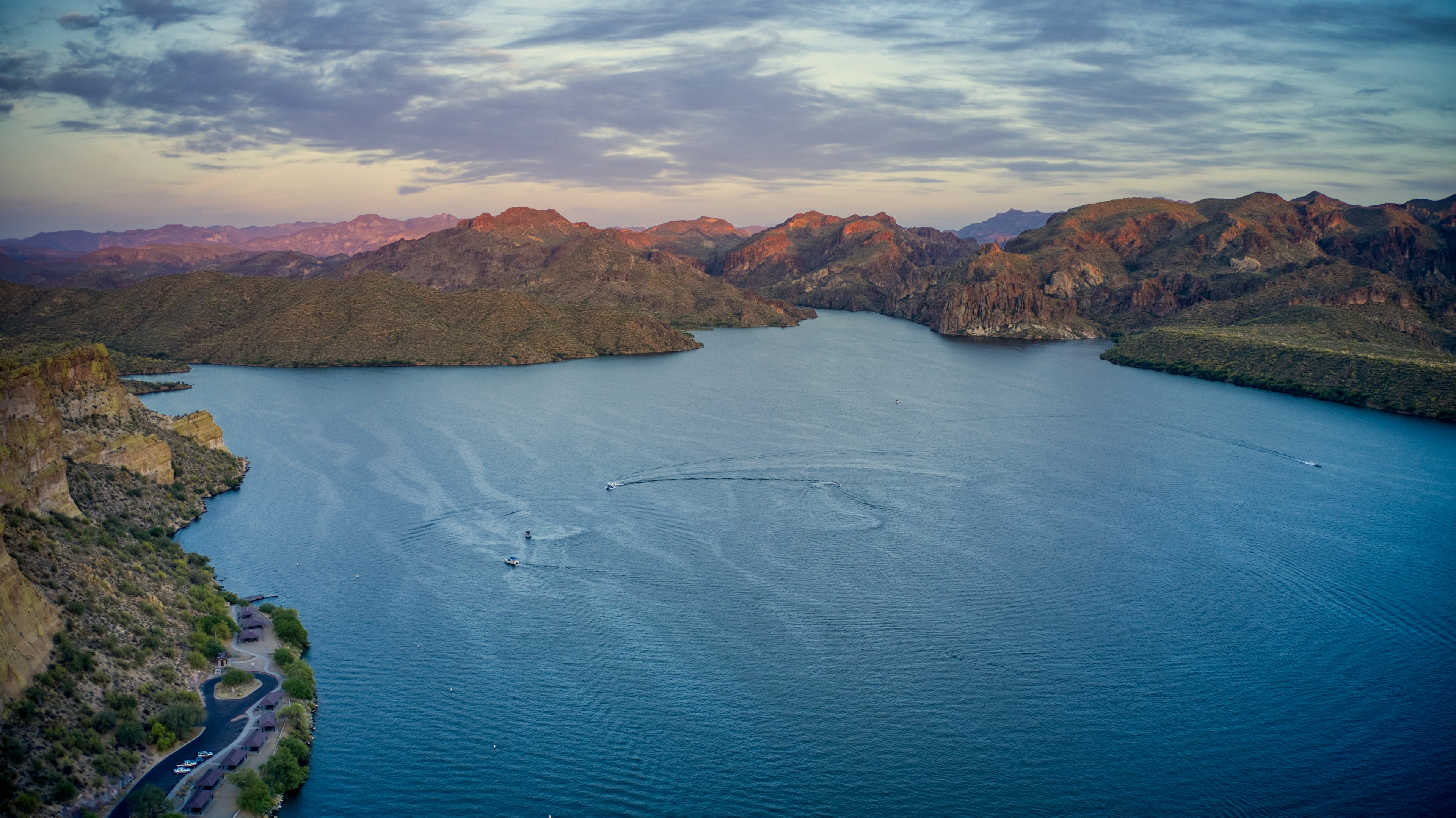 An aerial view of boats on a lake surrounded by mountains