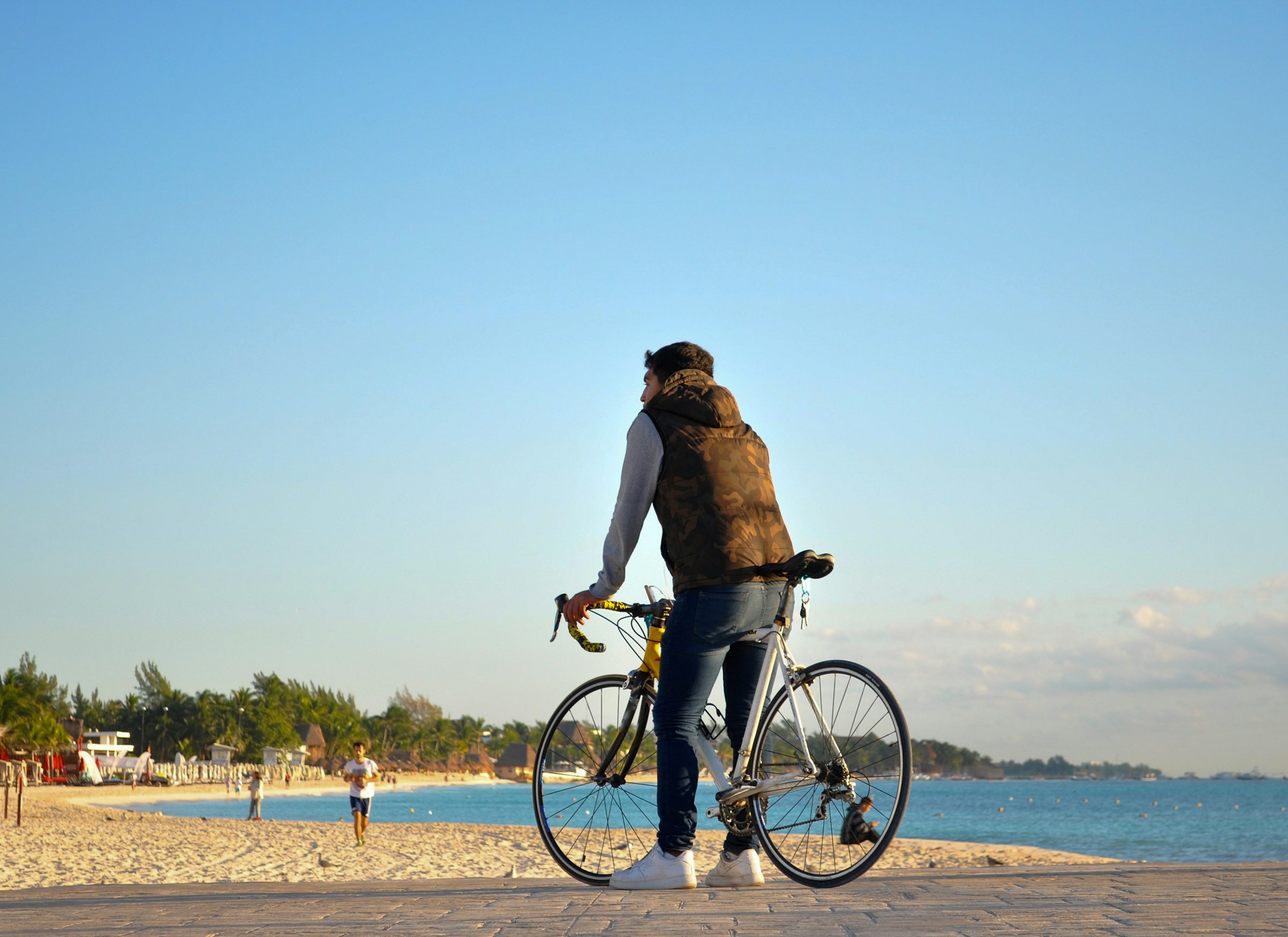 Young male standing on the beach with his bike on Playa del Carmen Mexico