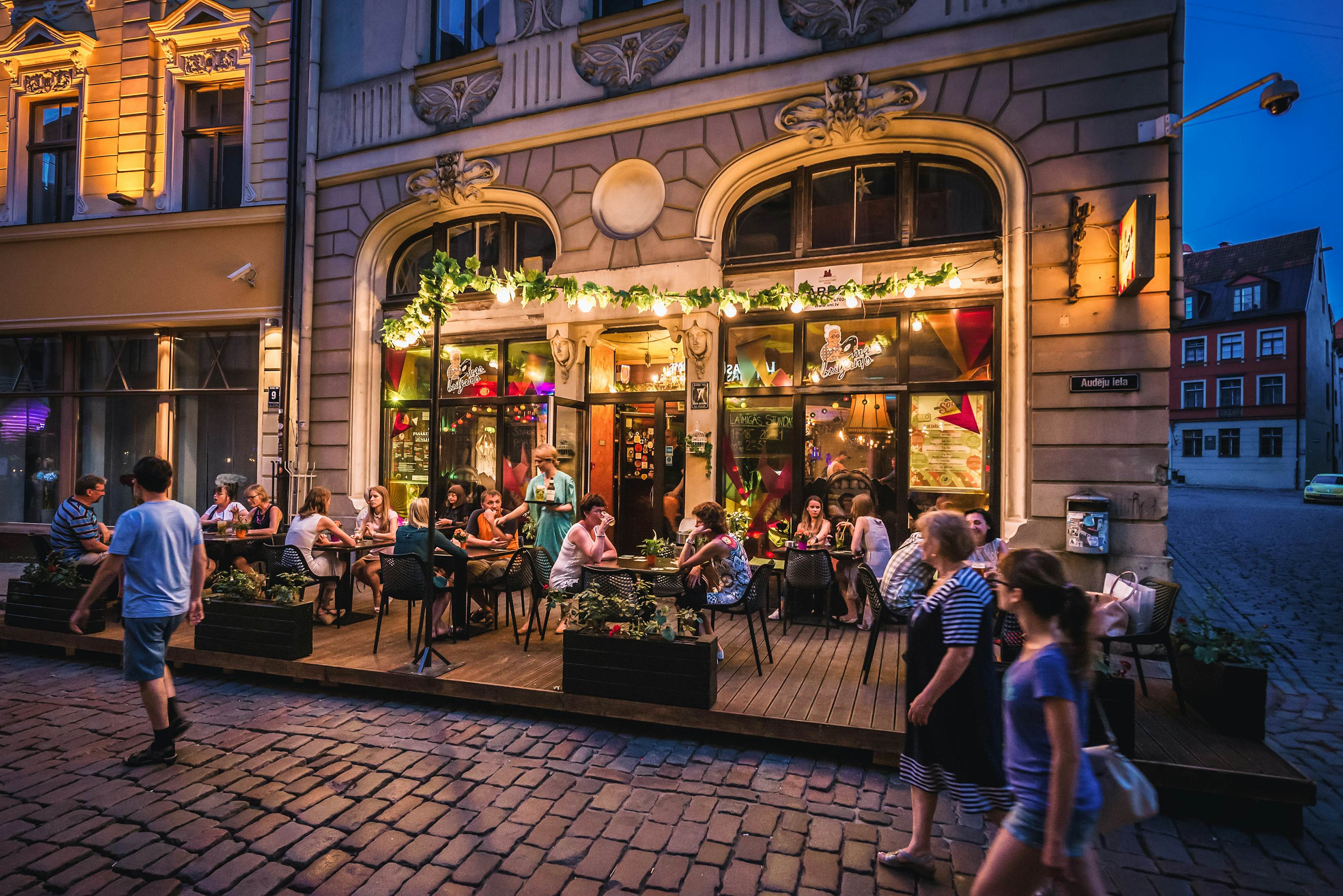 People sitting at a pavement cafeteria and pub located in the Old Town of Riga, Latvia.