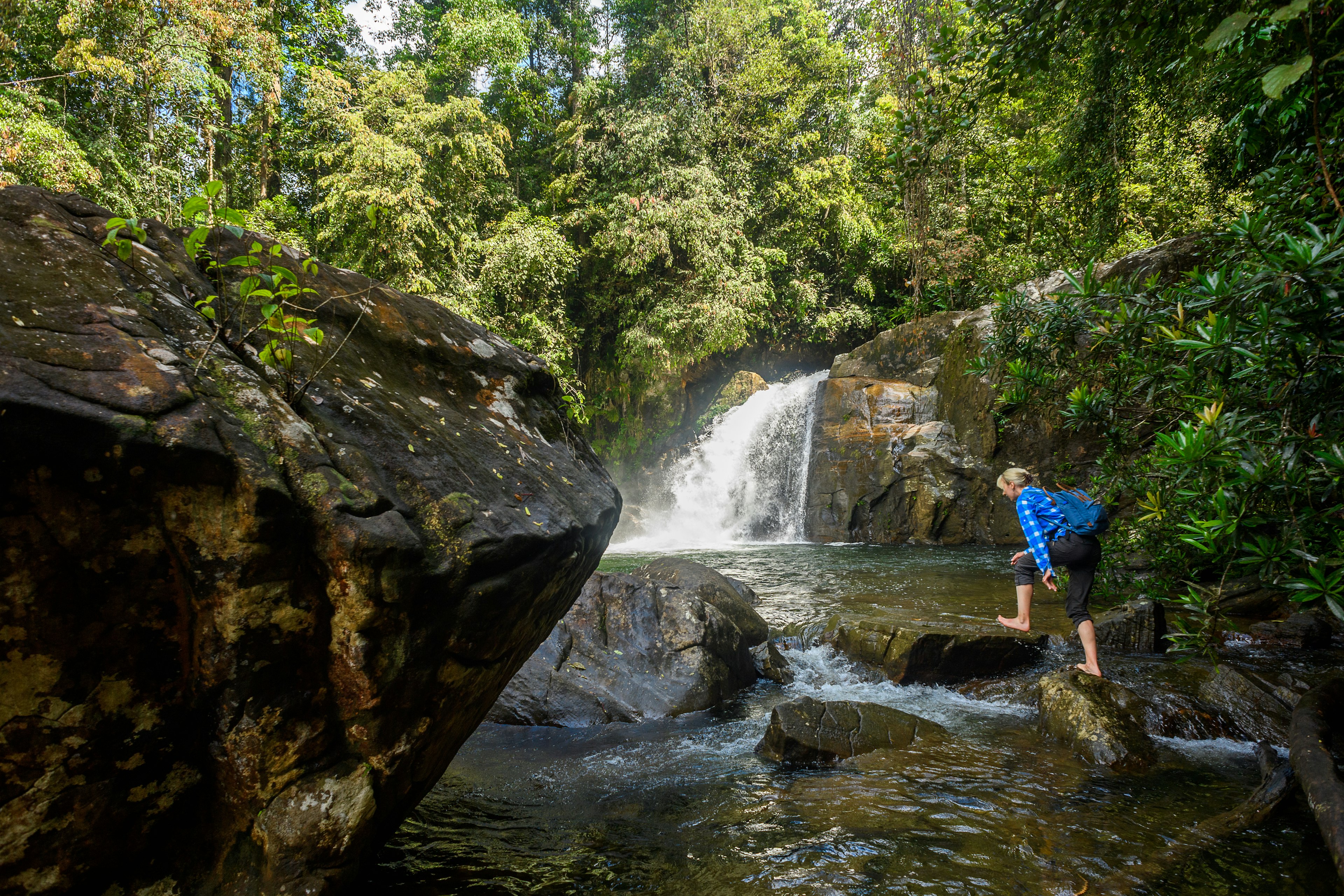 A girl crosses a waterfall in Sinharaja Forest Reserve