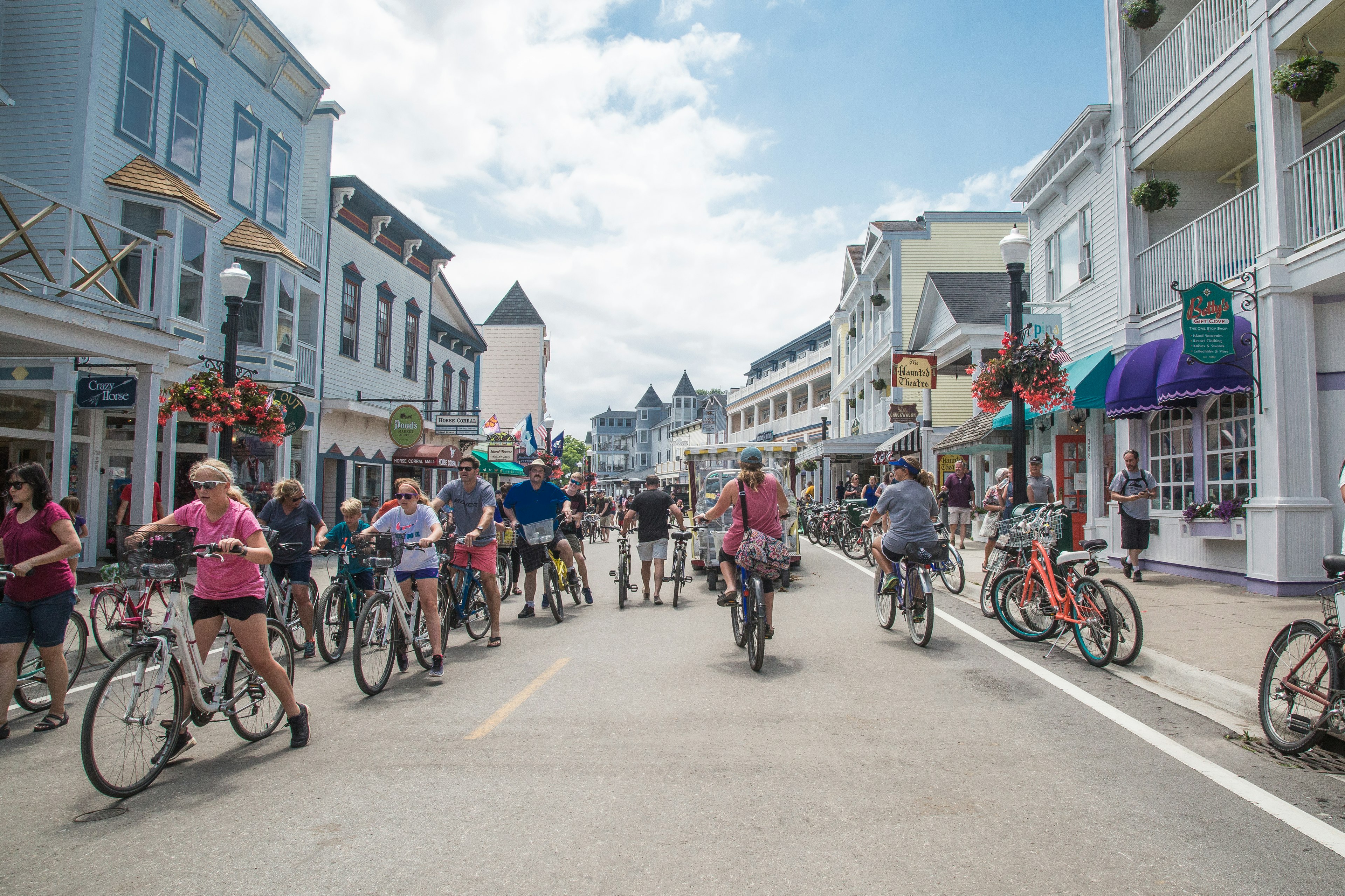 A car-free street lined with young and old people riding bicycles