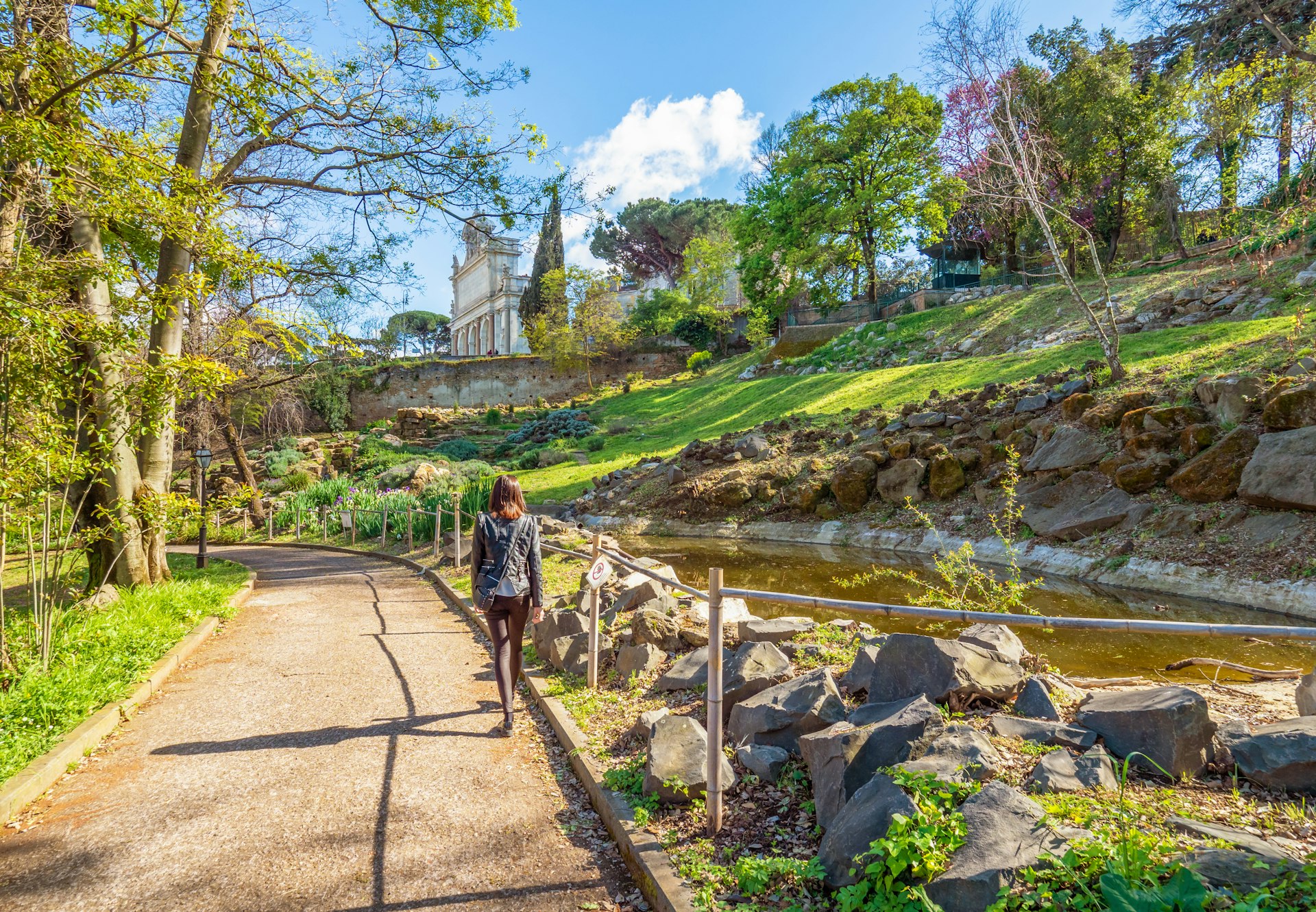 A woman walks through the lush grounds of the Botanical Garden in Trastevere