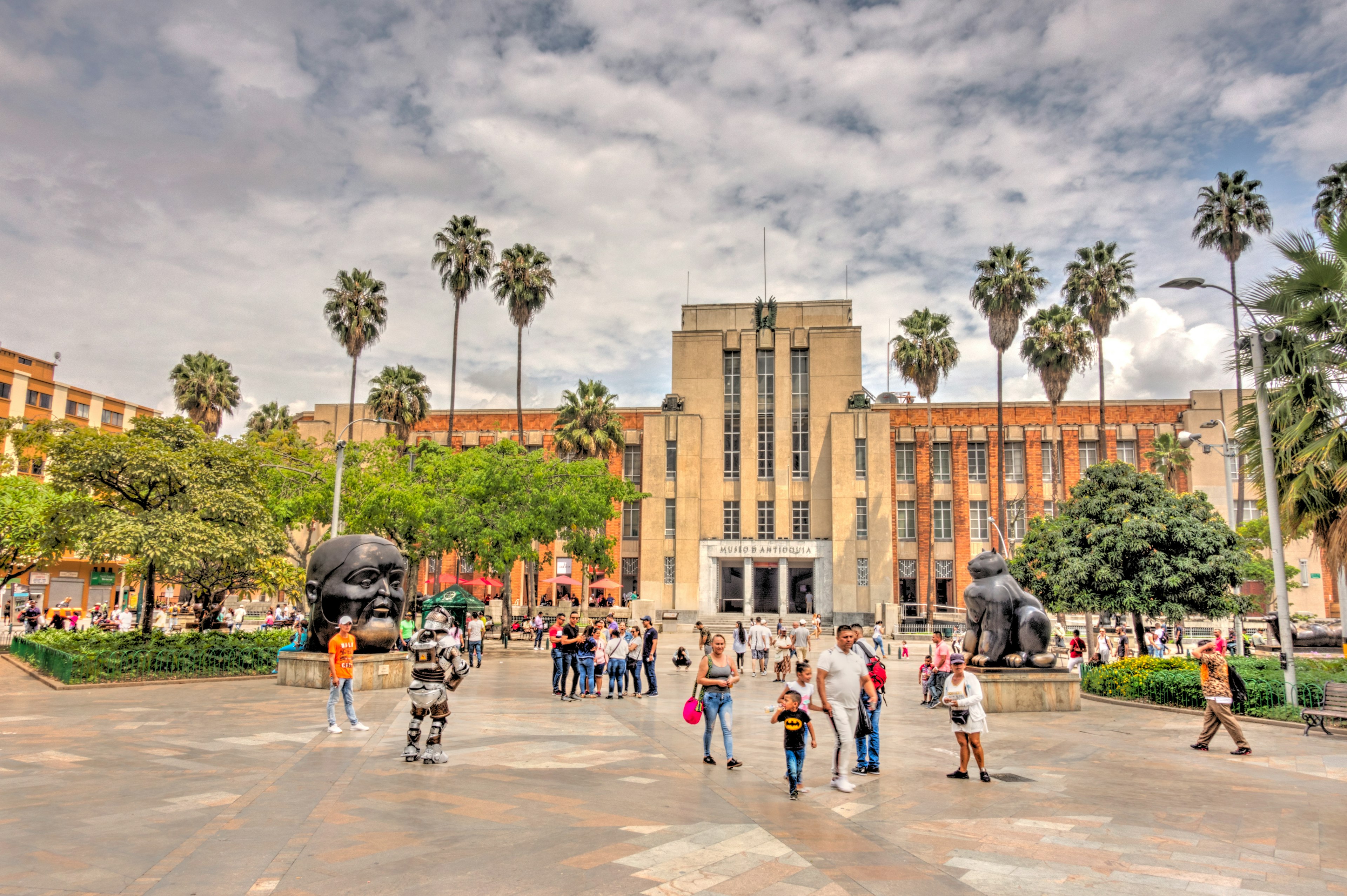 A large central square with huge bronze figurative sculptures backed by a large art gallery