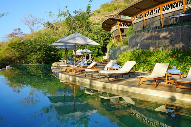 Sun loungers by a pool in an exclusive resort surrounded by jungle