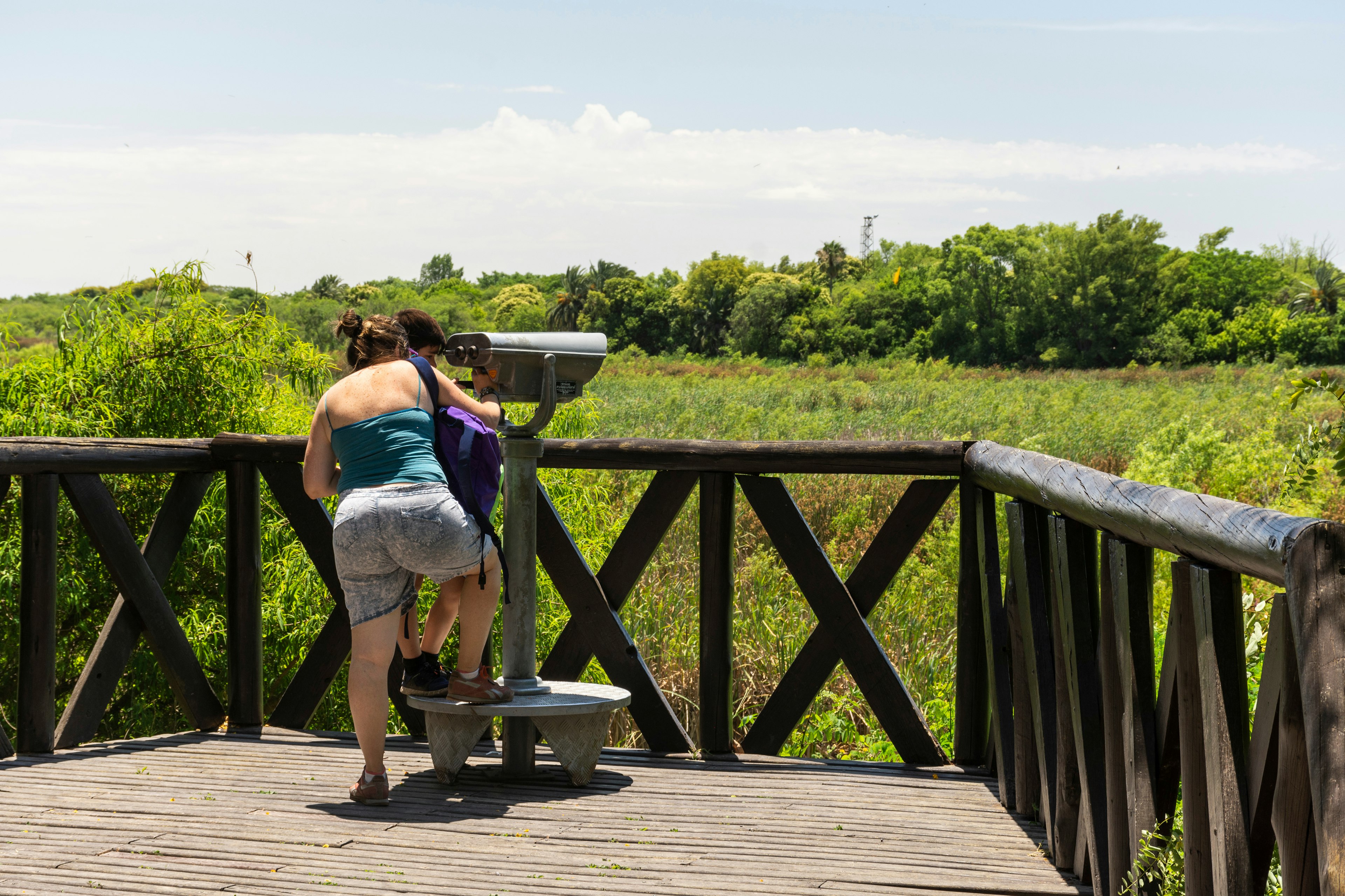 A woman and a child look through a telescope for wildlife in an eco park